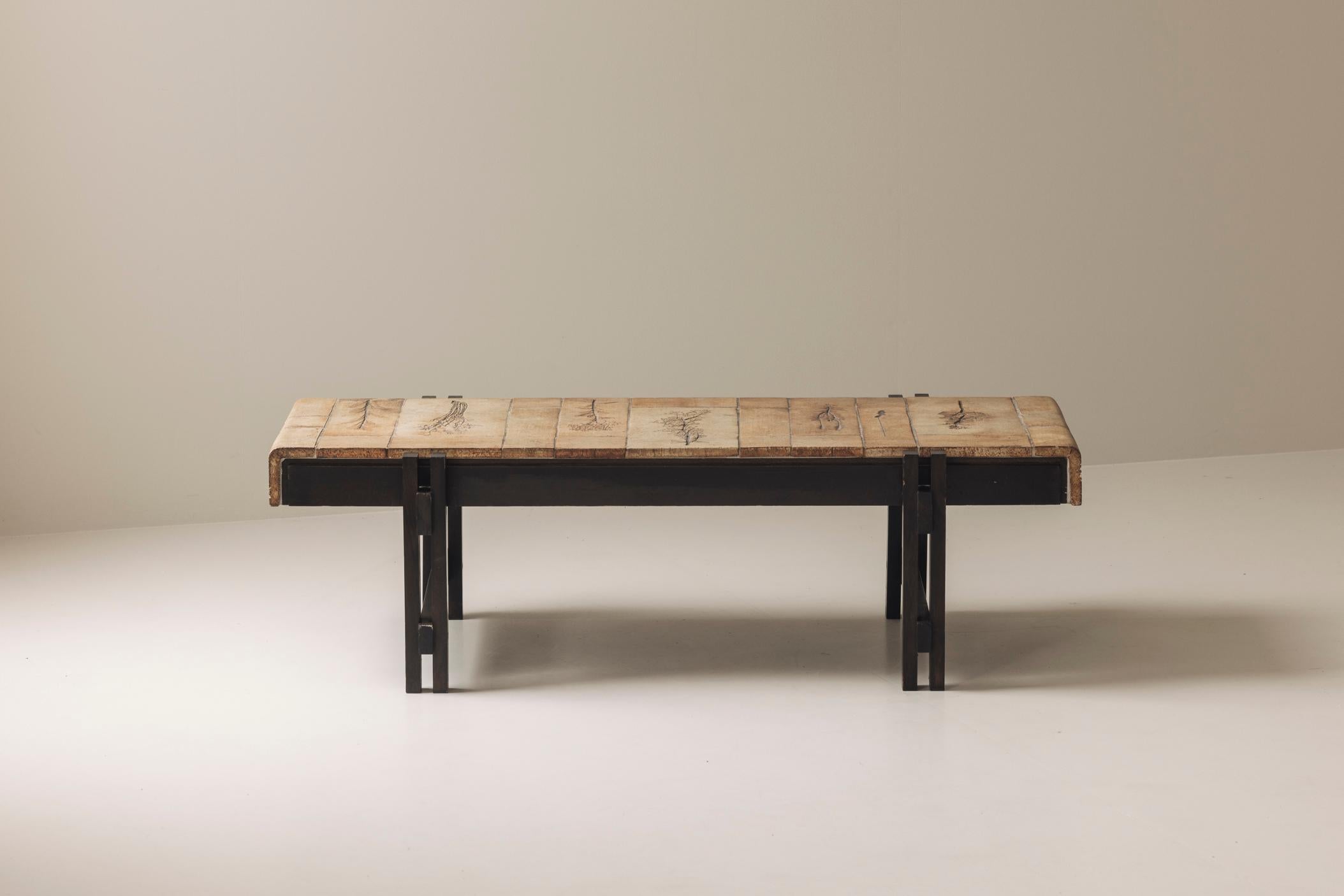 Lovely rectangular coffee table by Roger Capron, France 1960s. This piece features a beautifully dark stained wooden frame and a tabletop adorned with glazed ceramic sandstone tiles, each carefully decorated with botanical motifs. Presented in its