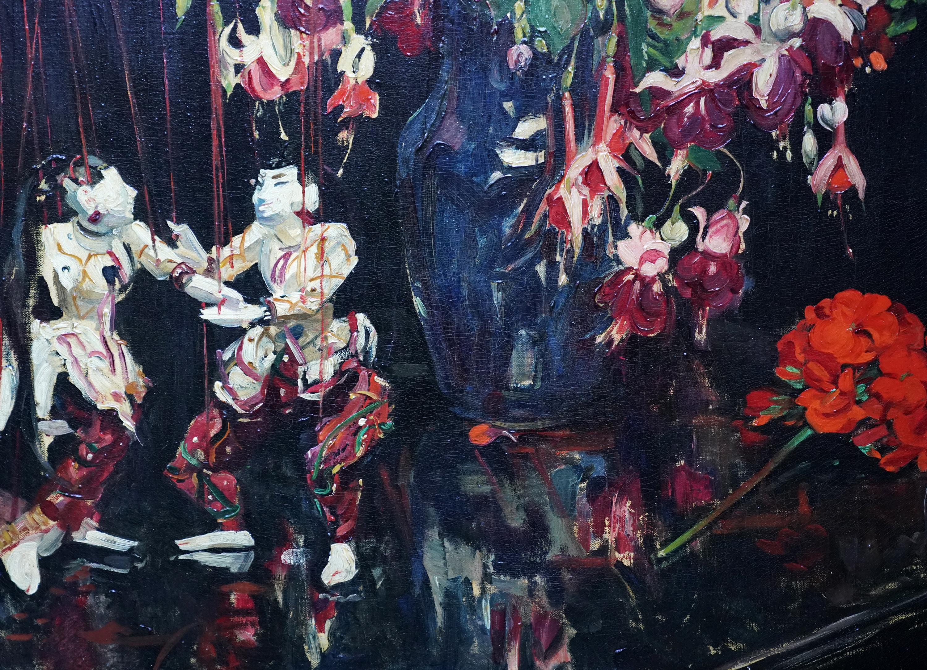 Cette charmante nature morte florale britannique est une peinture à l'huile de Herbert Davis Richter. Peint vers 1930, il représente un arrangement vibrant et intéressant de fuchsias et de géraniums dans un vase à côté d'un couple de marionnettes.