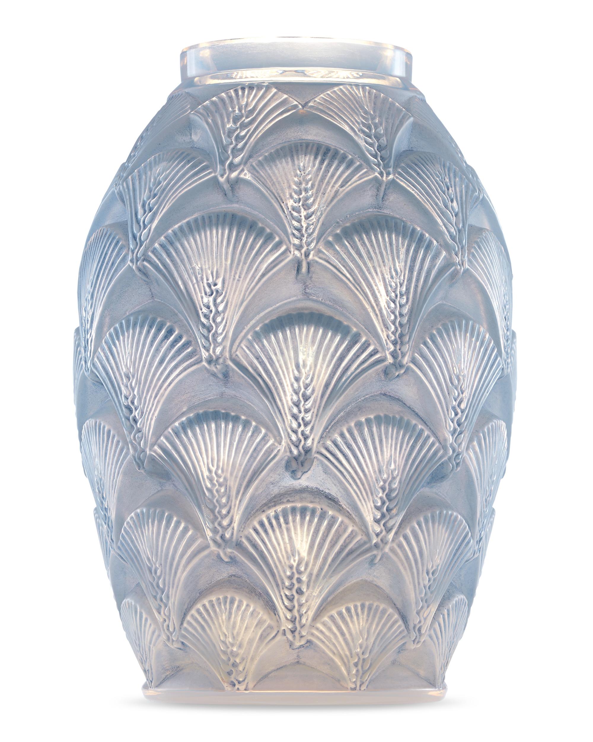 The work of famed French glass master René Lalique, this dynamic vase is crafted in the rare and intricate Herblay pattern. Conceived in 1932 during the height of Art Deco, its design is formed from opalescent, blue stained glass that features an