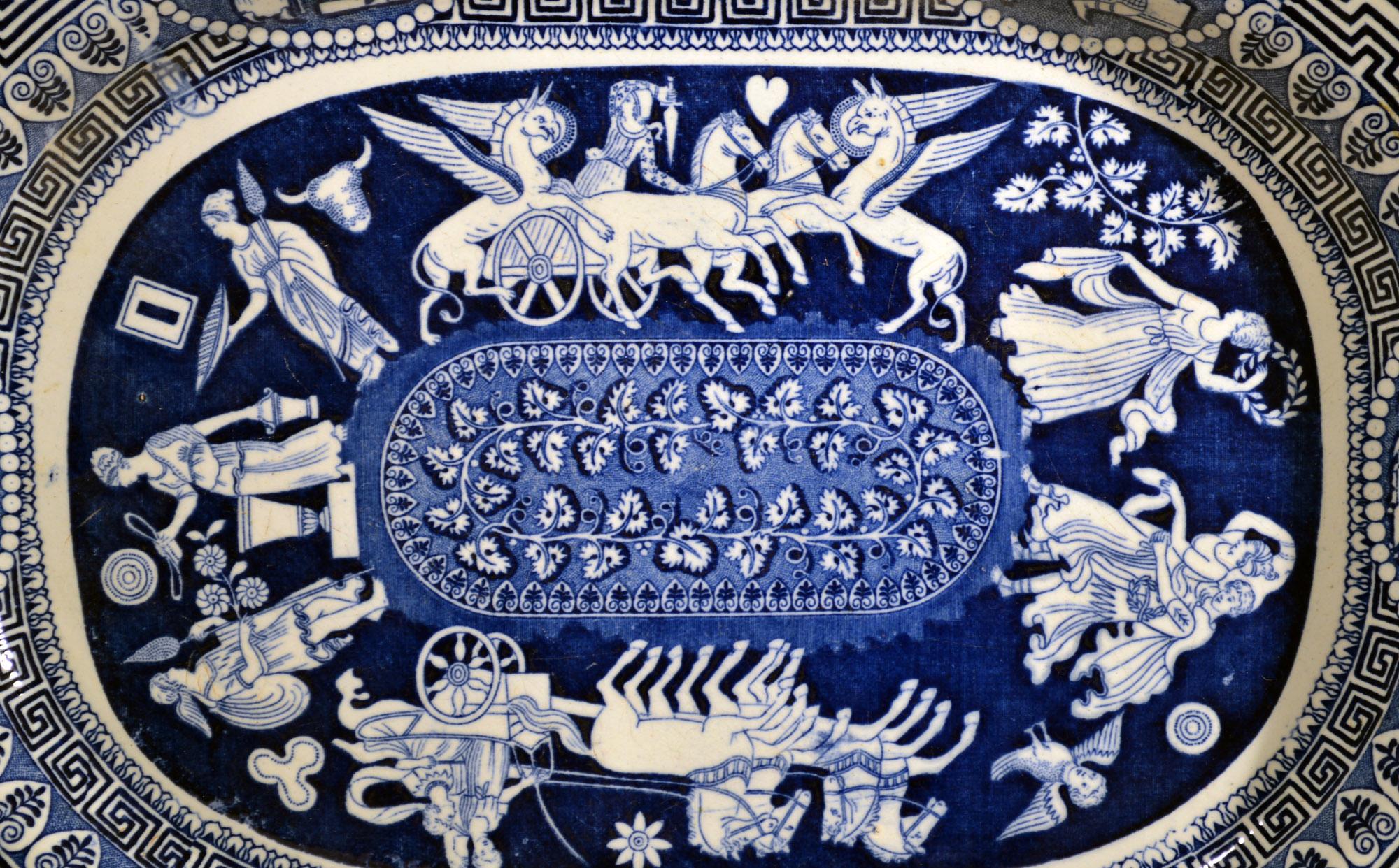 Herculaneum Neo-classical large Greek pattern blue printed dish,
Early-19th century

The Herculaneum pottery underglaze blue central pattern shows aseries of images encicling an oval panel with a leafy vine. There are two main images, one with