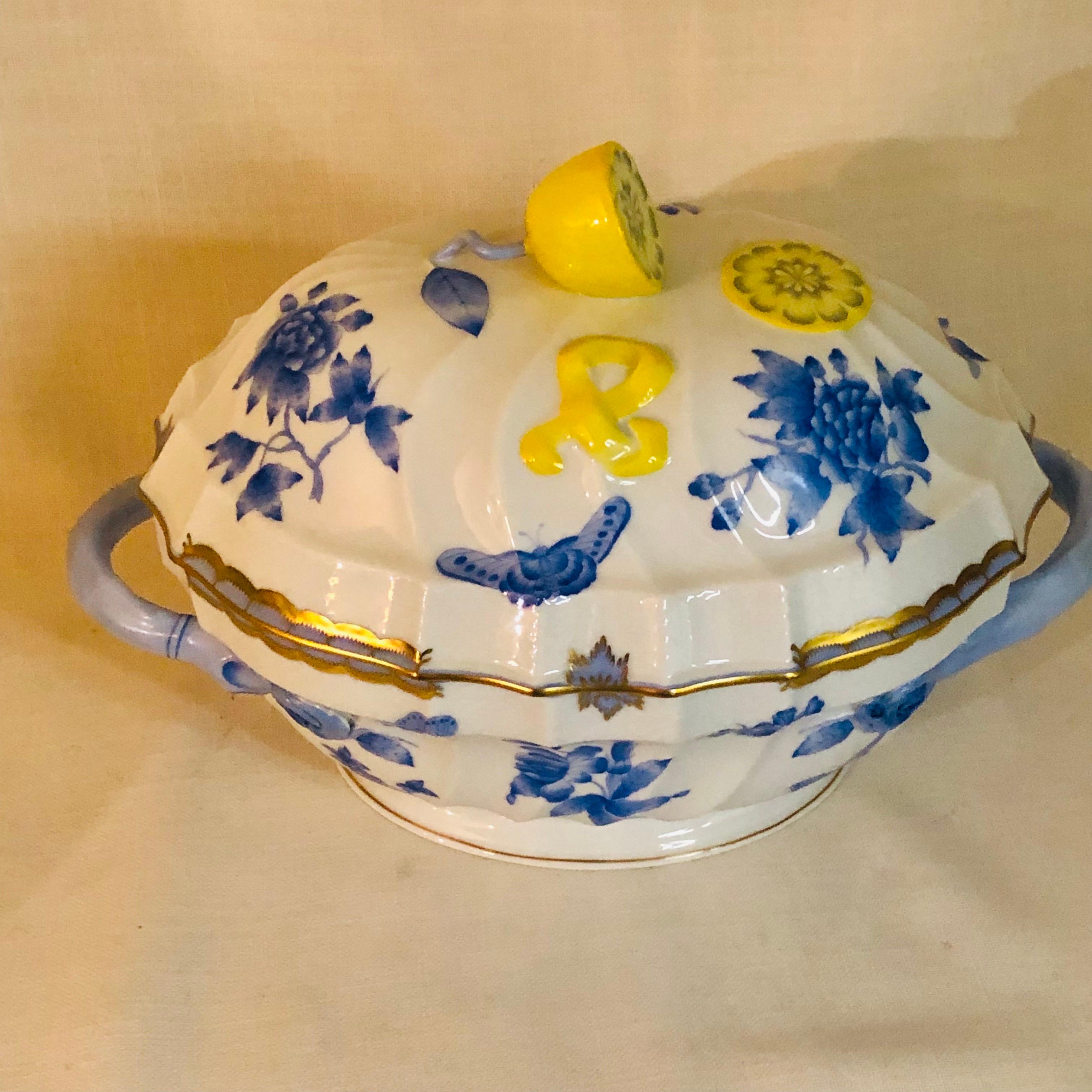 This is a beautiful Herend Fortuna soup tureen painted with blue butterflies and flowers on a white background with 24 karat gold accents. It has a wonderful shaped lemon on its cover. It would be a charming decorative piece on your dining room