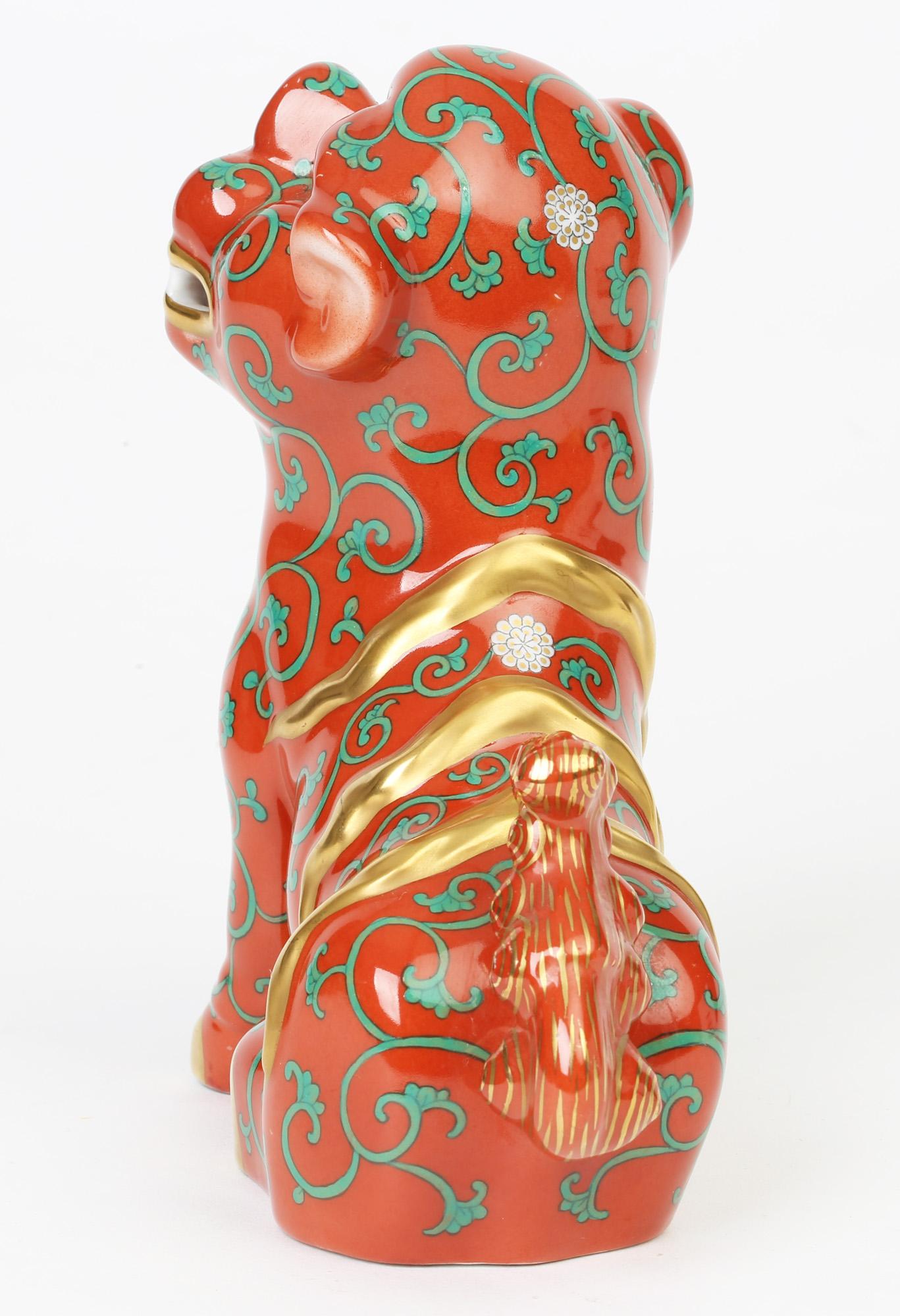 A stylish Hungarian porcelain Oriental Foo Dog figure painted in Special Godollo Red and made by Herend, circa 1950. The figure stands facing right with one front paw raised and is painted with a scroll and floral pattern on rich brick red colour