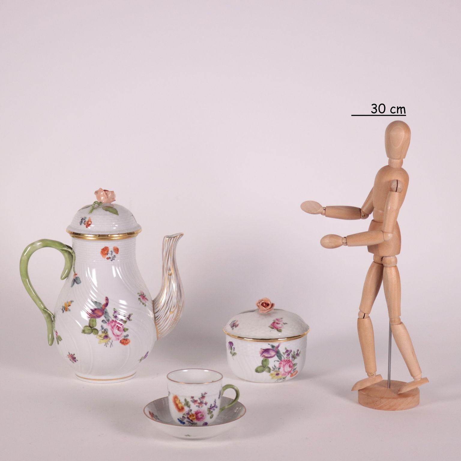 Service à café en porcelaine décoré de motifs végétaux, bords dorés, poignées du couvercle en forme de roses. Marque du fabricant sous la base. Il est composé d'une cafetière, d'un sucrier, d'un crémier et de 12 petites tasses avec assiette.