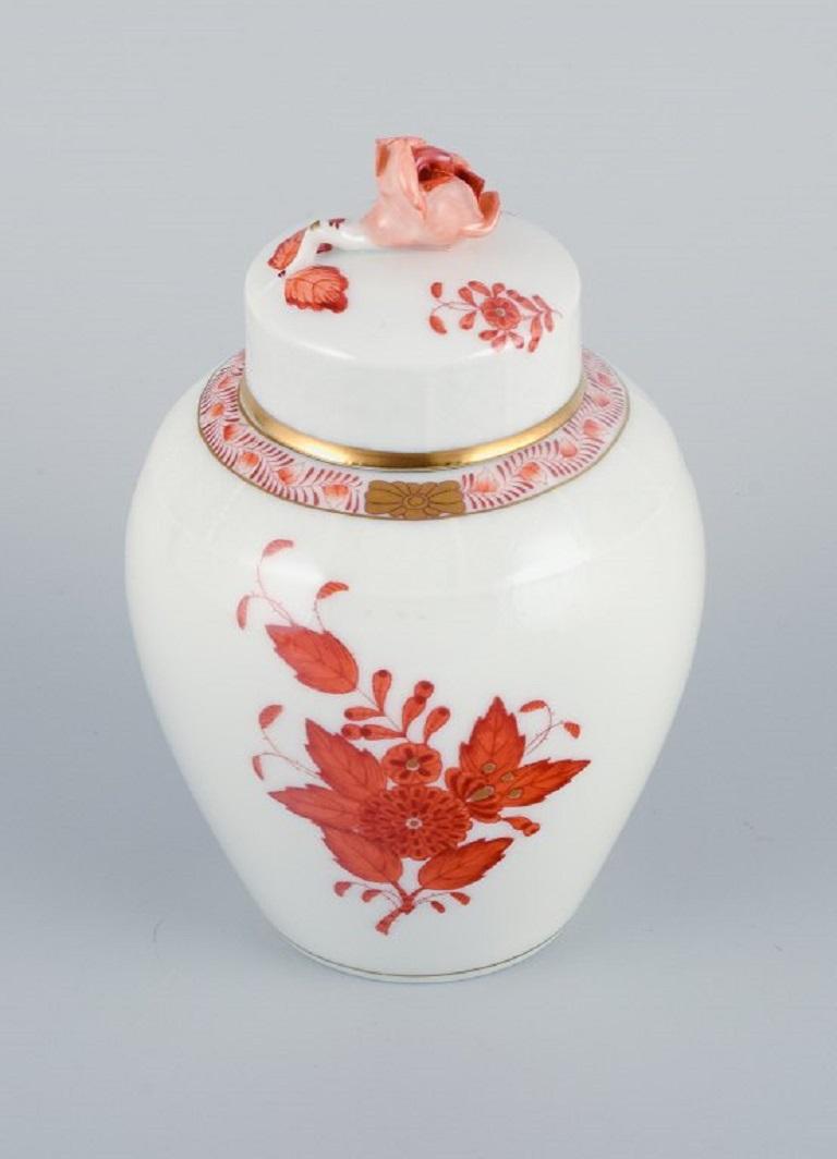Herend, Hungary. Porcelain urn style vase with a lid. 
Decorated with hand painted orange flowers, golden rim and a moulded flower on the lid.
Mid-20th Century
In excellent condition.
Stamped
Measures: H 14.0 cm. x D 9.5 cm.
