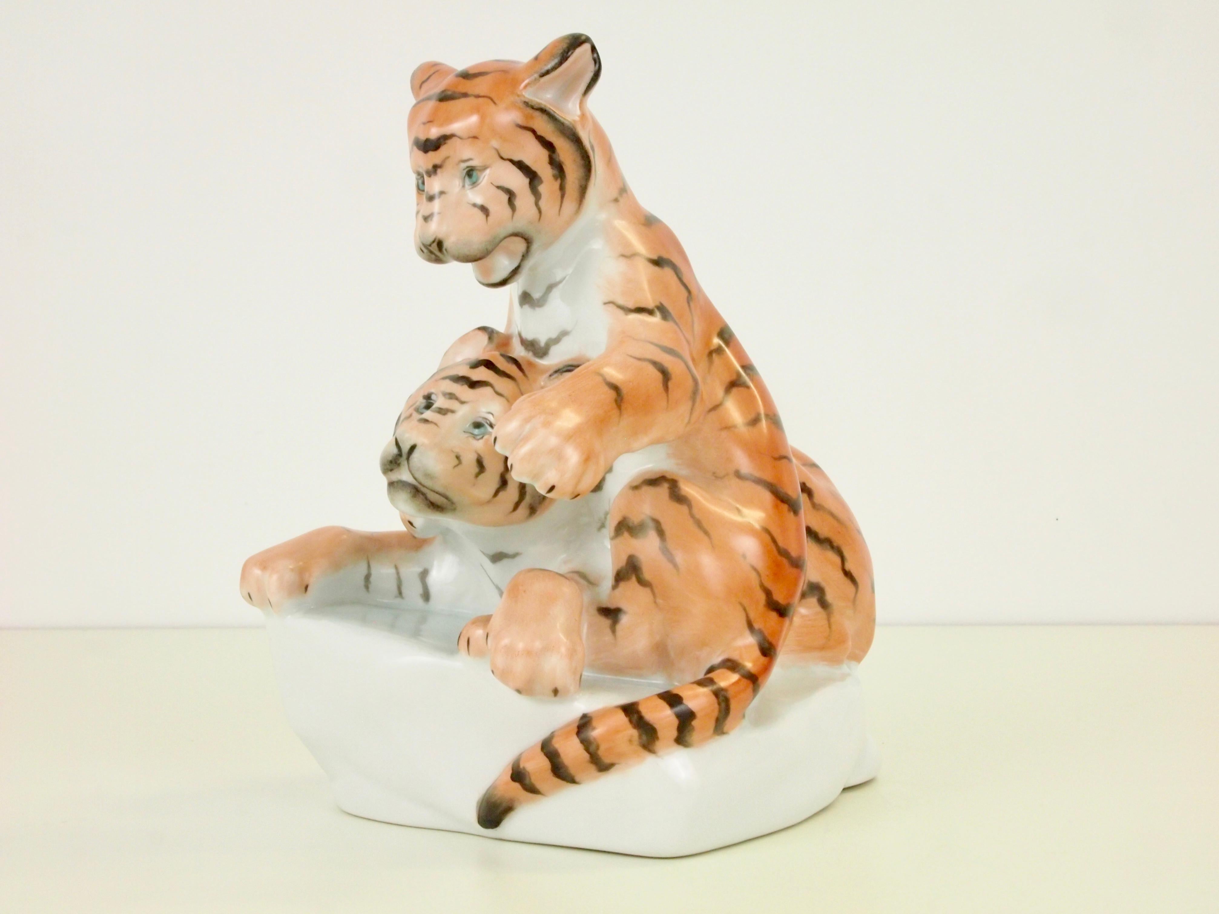 Vintage midcentury porcelain figurine by Herend depicting a couple young tiger cubs playing joyfully together.

Herend was founded in 1826 and has had much famous customers who bought its porcelain. At the first World's Fair the porcelain