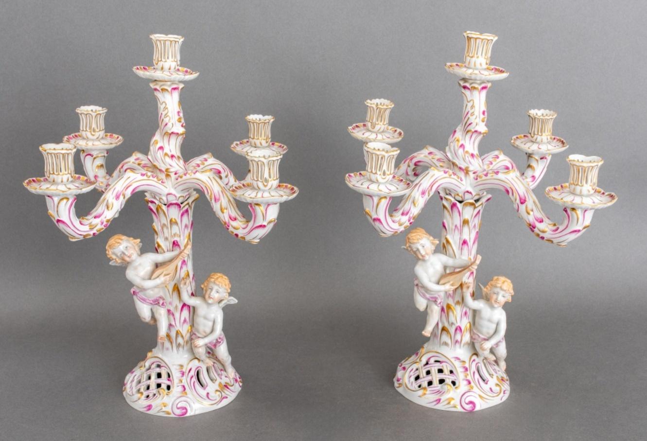 Pair of Herend Hungarian porcelain five-light cherub candelabra, 2, each with blue overglaze marks for Herend, 1950s, each of palm and rocaille form with two naturalistically painted cherubs with musical attributes,  overall decorated in Rose