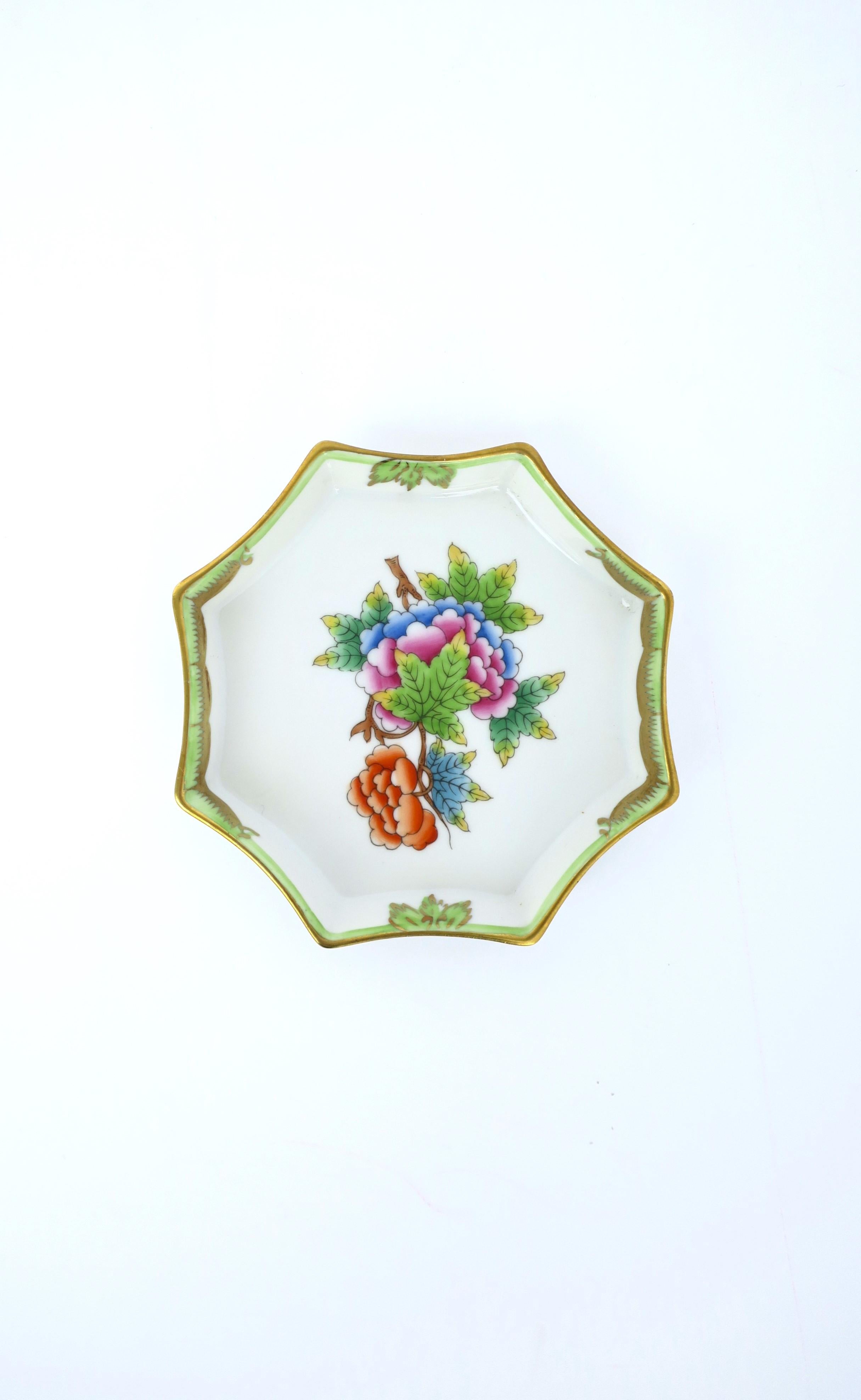 A very beautiful hand-painted octagonal porcelain jewelry dish vide-poche from luxury maker Herend, circa 20th century, Hungary. Dish is octagonal with Queen Victoria design, a floral and leaf center and decorative edge finished in gold. Colors are