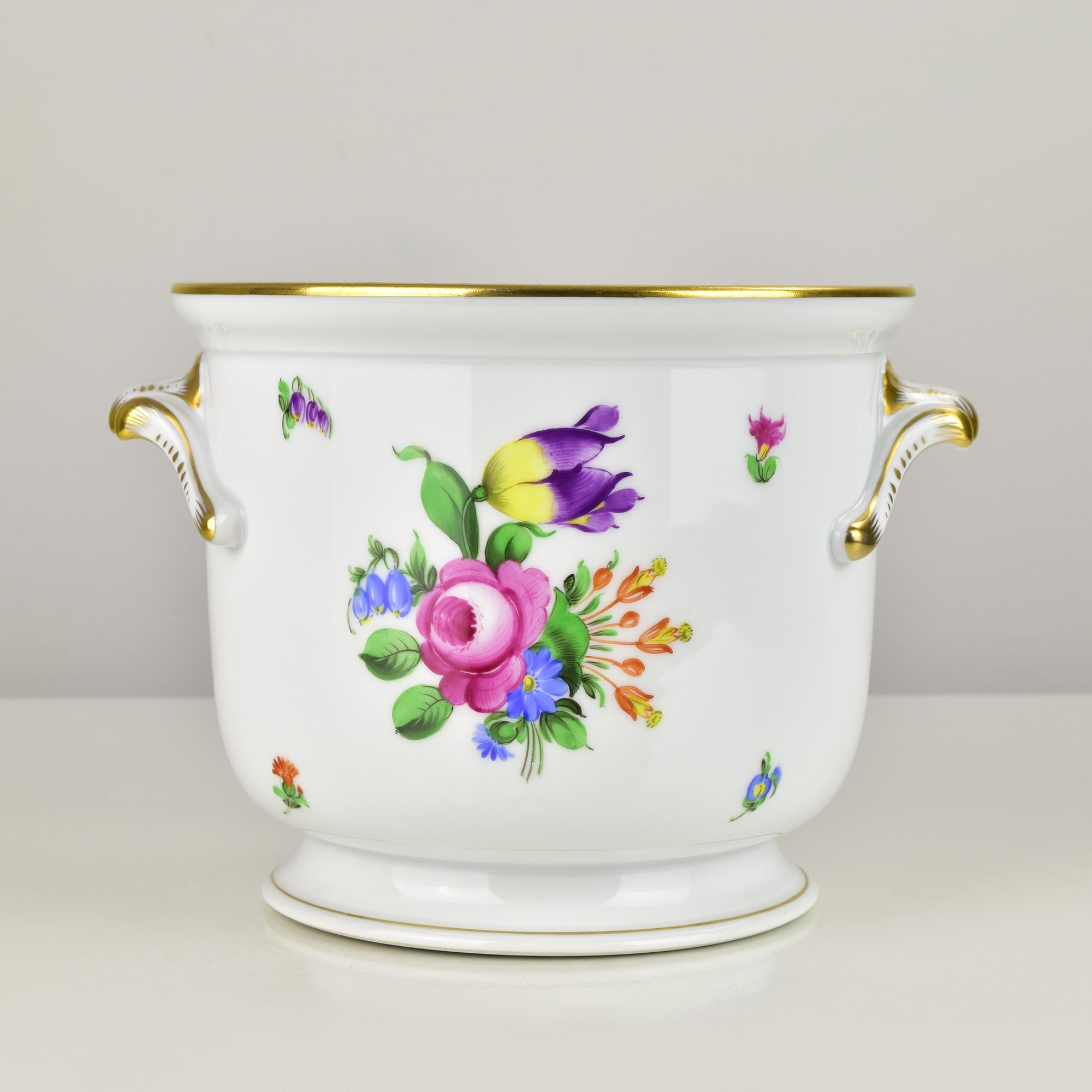 Elegant Herend Hungary porcelain cachepot, masterfully hand-painted with vibrant floral bouquets on a crisp white ground. The piece features two finely shaped side handles highlighted with lavish 24K gold accents, along with a gilt rim that enhances