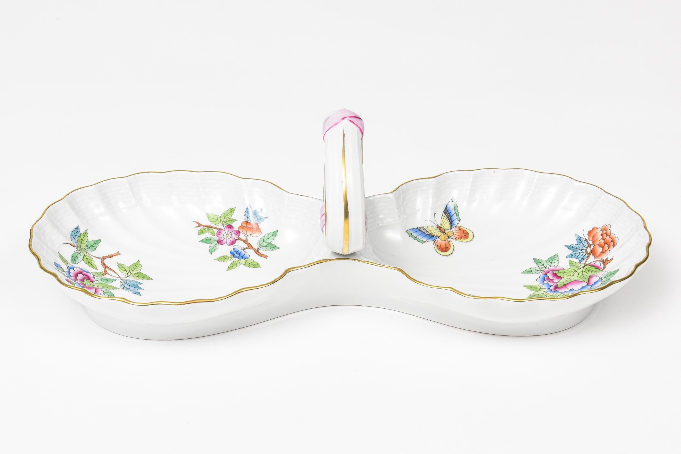 Elegant Herend China 2-part relish dish. This is the older pattern of Queen Victoria that does not have the green border. It has a weave rim and a gold edge. The pattern features flowers and butterflies and a pink ribbon accent on the handle.