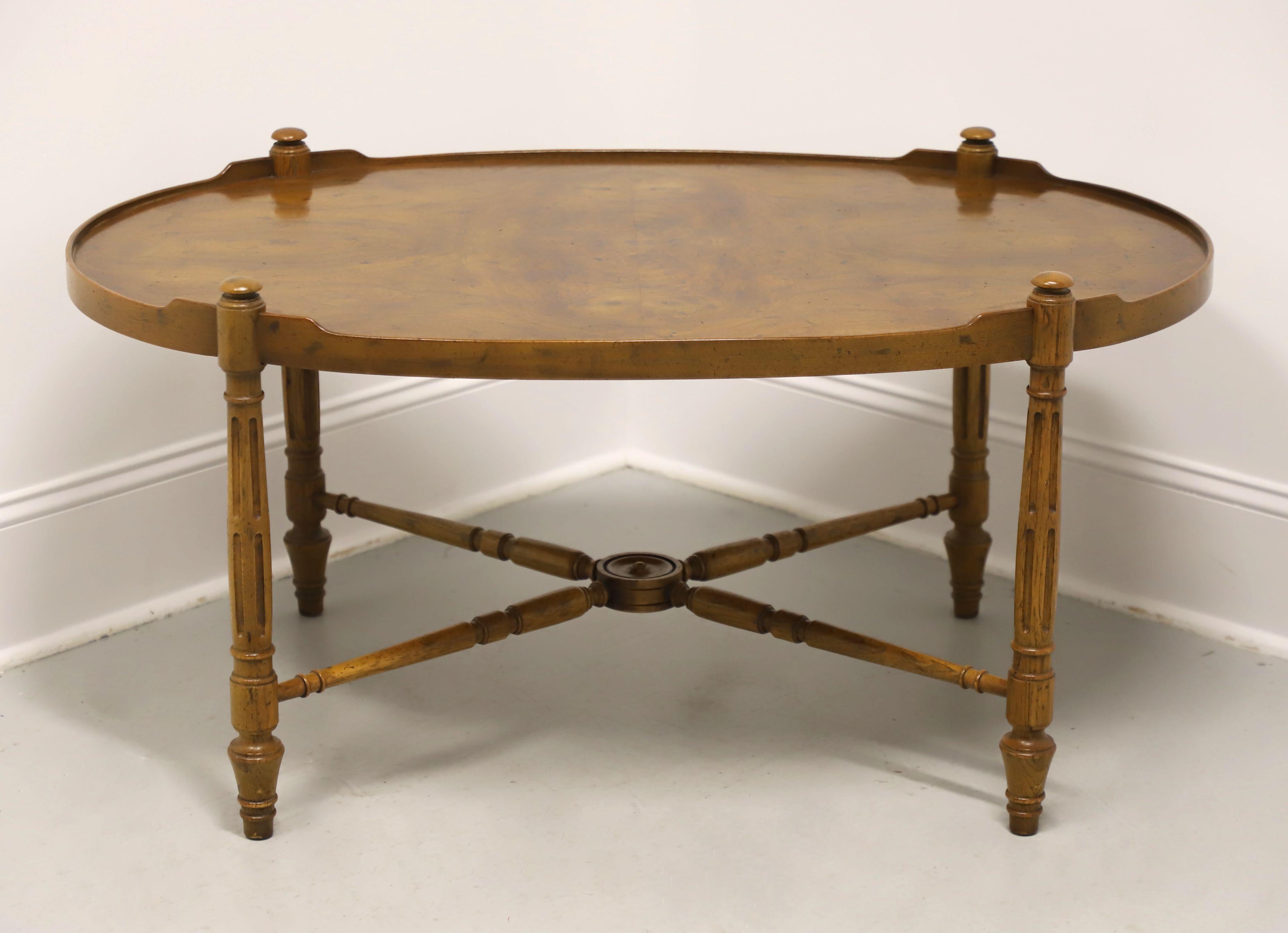 A French Provincial Louis XVI style oval coffee table by Heritage Furniture. Walnut with a burl walnut top, rounded raised edge to the top, fluted column-like legs with decorative button caps at tops, turned 