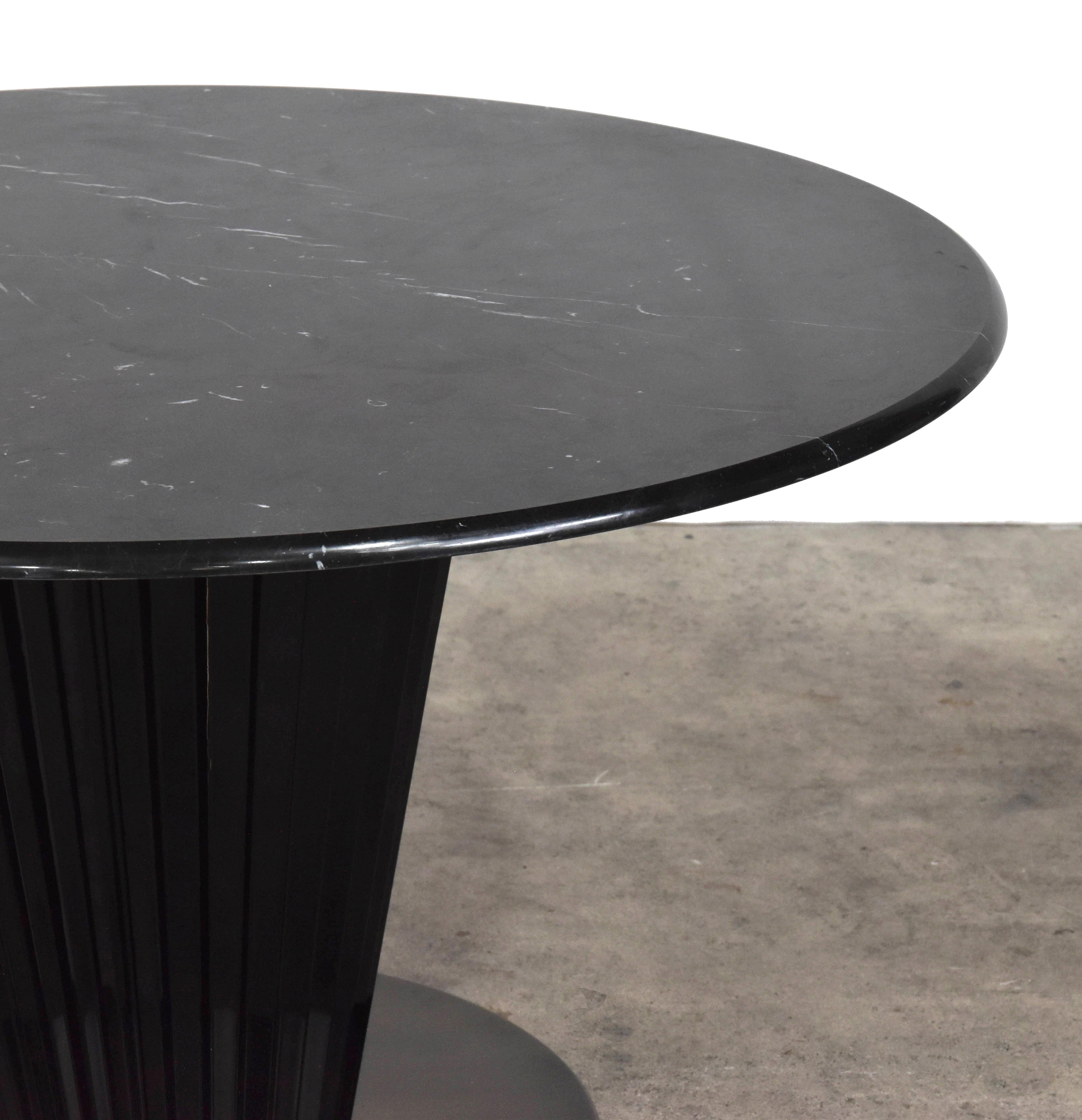 La table Royal est d'inspiration Art Déco avec un plateau en marbre Marquina, un piédestal en laque noire brillante avec des détails cannelés.
    