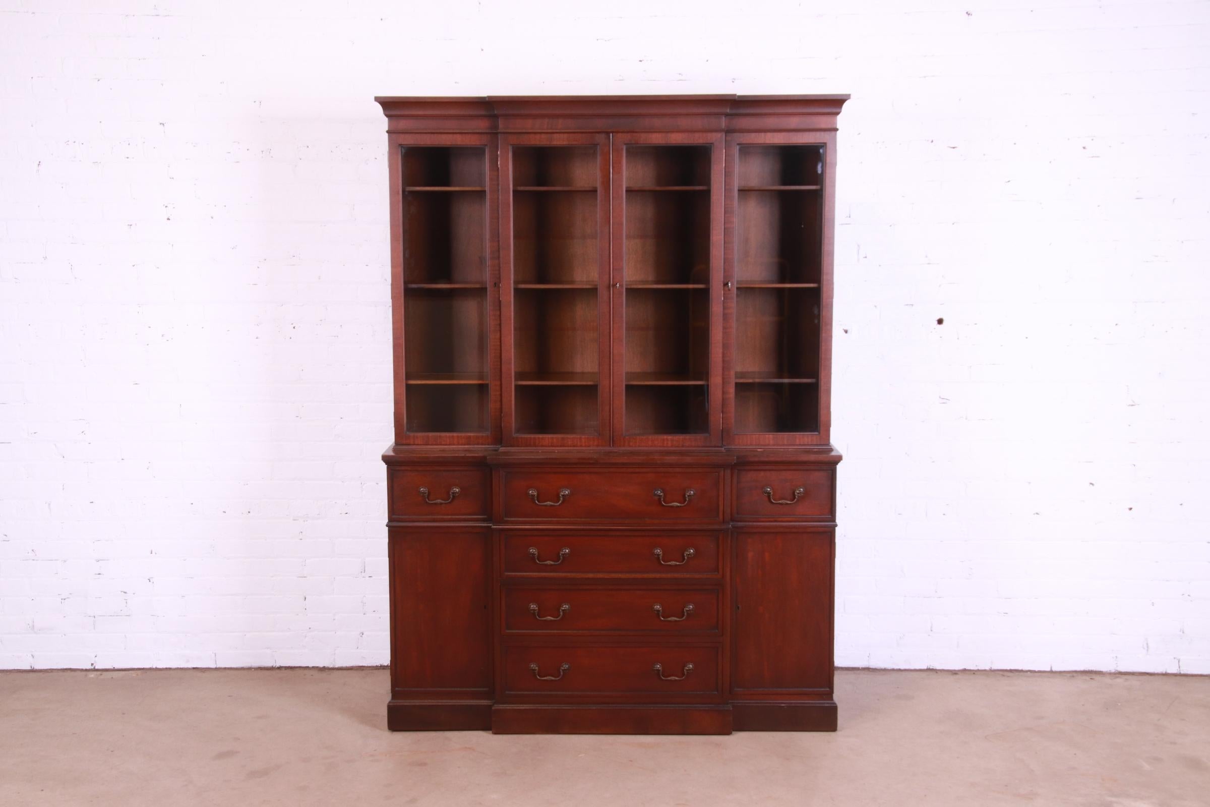A beautiful Georgian style breakfront bookcase cabinet with secretary desk

By Heritage Henredon

USA, Circa 1960s

Mahogany, with glass front doors, original brass hardware, and embossed leather writing surface. Cabinet locks, and original