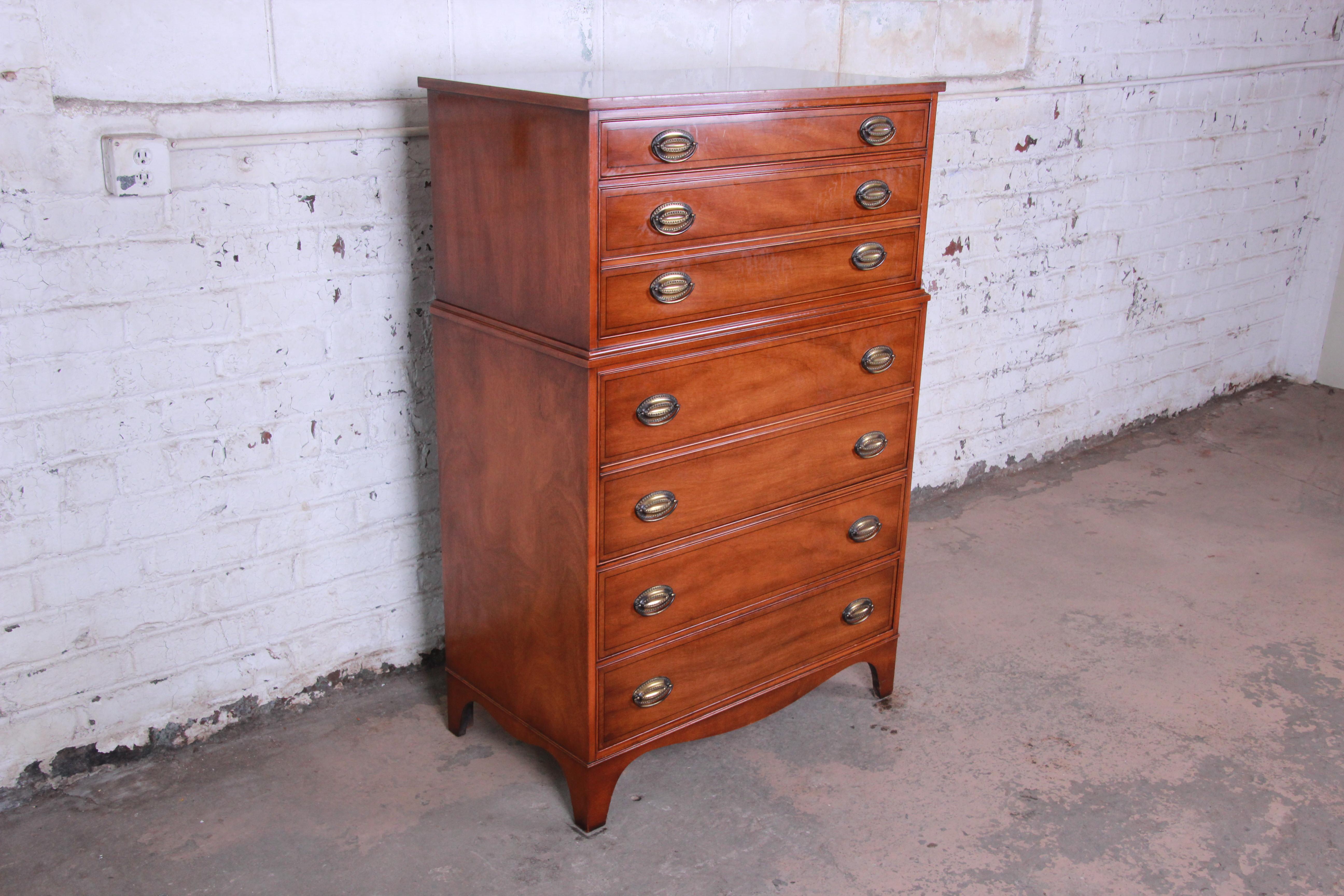 A gorgeous inlaid mahogany highboy dresser by Heritage Henredon. The dresser features stunning mahogany wood grain and a nice traditional style. It offers ample storage, with four dovetailed drawers and two drop-down compartments each with three