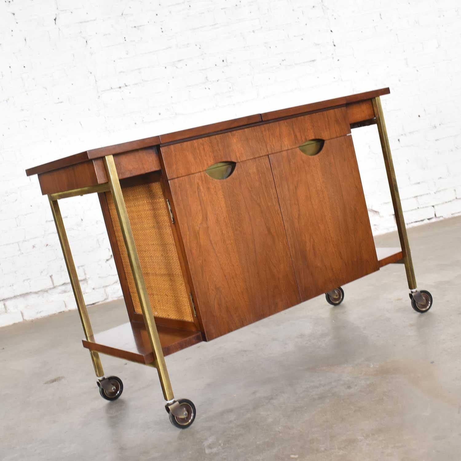 Attractive Mid-Century Modern walnut and cane rolling bar cart with Heritage stamped inside its drawer. This cart has only been cleaned and although there are a few minor scratches on the top, it is in fabulous vintage condition. One of the brass