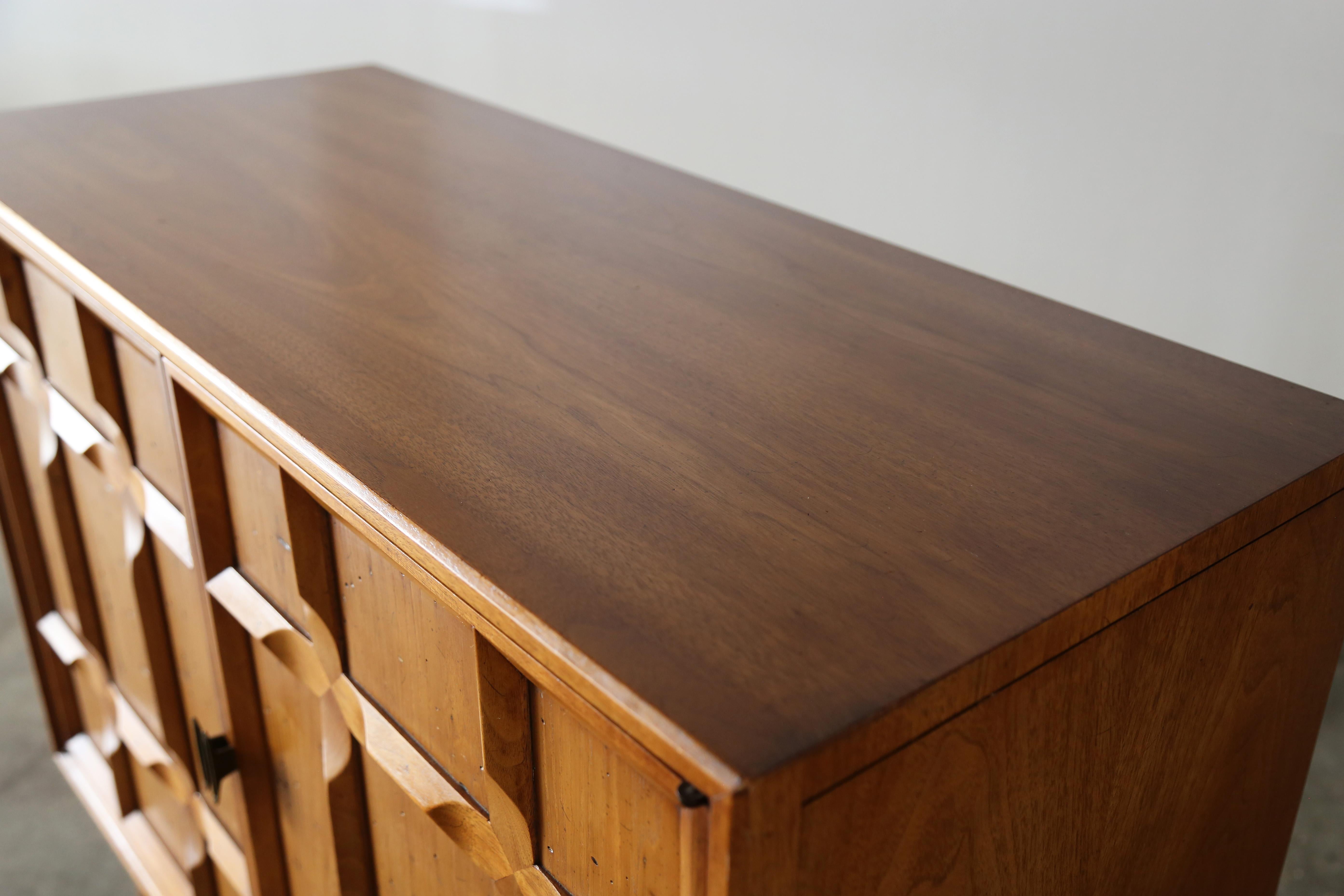 A great cabinet designed by Heritage. A sculpted front reminiscent of Edmond J Spence with angled legs, and inset diamond shaped doors. Small Cabinet with a large impact. The distressed doors open to two drawers and an adjustable shelf. Great
