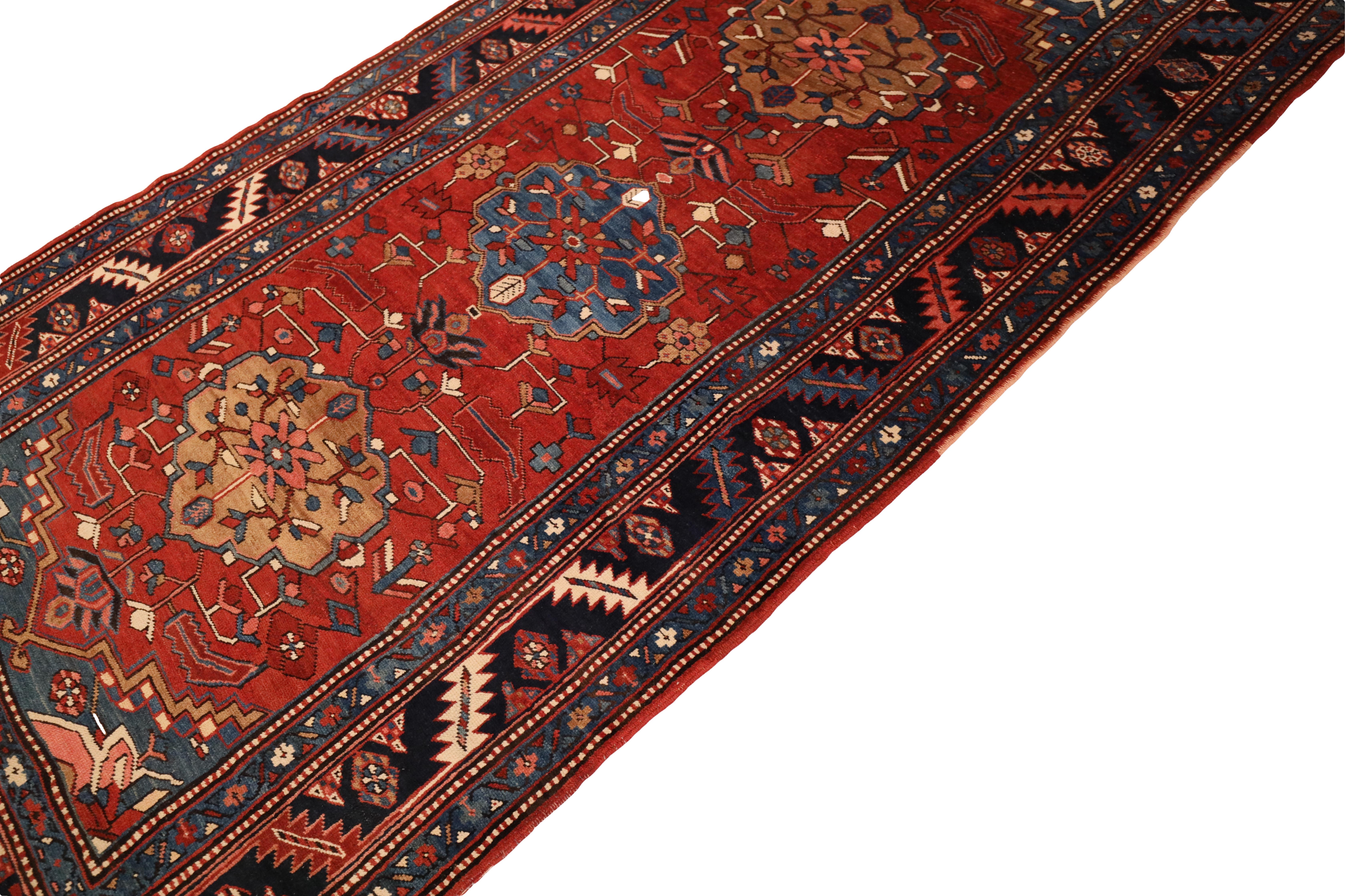 This exquisite antique Heriz carpet is a true masterpiece of Persian rug weaving. The rich ruby red background immediately catches the eye, exuding warmth and vibrancy. Three stunning medallions, alternating in beige, blue, and beige, run down the