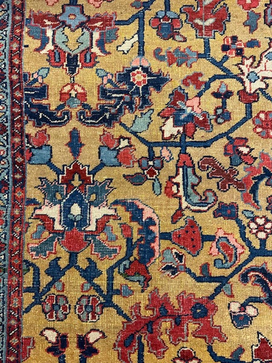 Dieser gelbgrundige nordwestpersische Heriz-Teppich zeigt ein zentrales Muster, das sich aus einem Zentrum mit acht Blütenblättern entwickelt, von dem aus Palmetten und Blätter ausstrahlen.Die gebrochene Weinrebe trägt weitere Blätter, Rosetten,