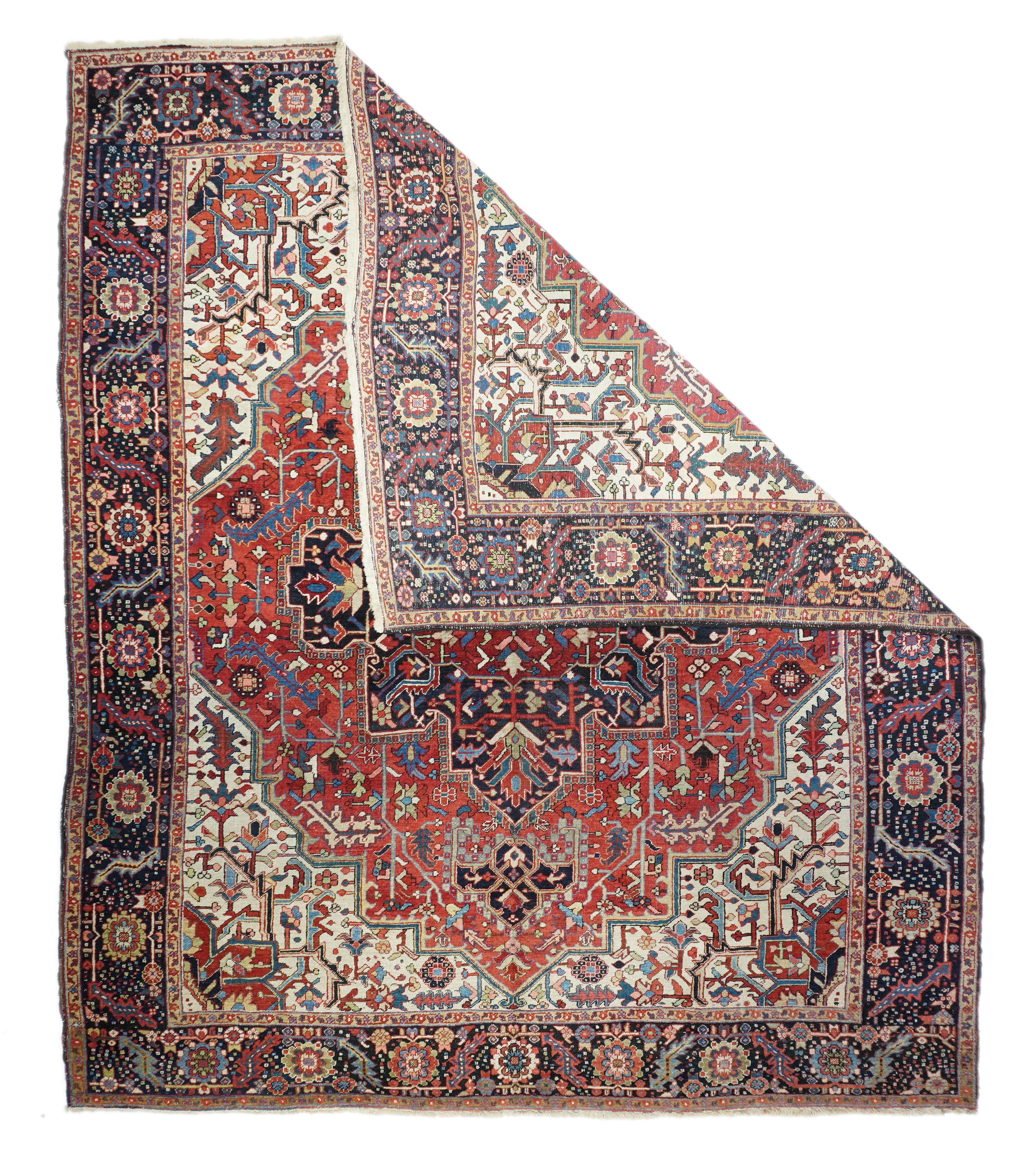 This well-woven, “Serapi” quality room size rustic carpet shows a stepped and angled abrashed red field supporting a pendanted navy stepped and lobed medallion with an inner blood red square floral cartouche. Ecru corners with mobile formal vinery