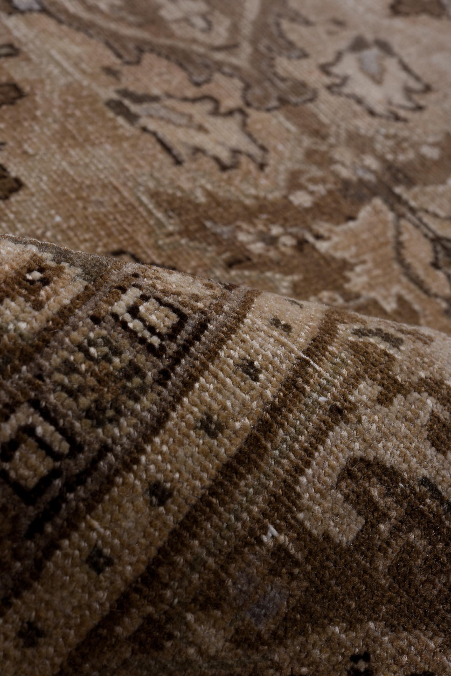 This Heriz displays a subdued palette of taupe, sand, and faded olive with powdery blue accents. The layered medallion structure is anchored by stylized floral motifs, framed by a thick scrolling border. Its time-worn surface and restrained tones