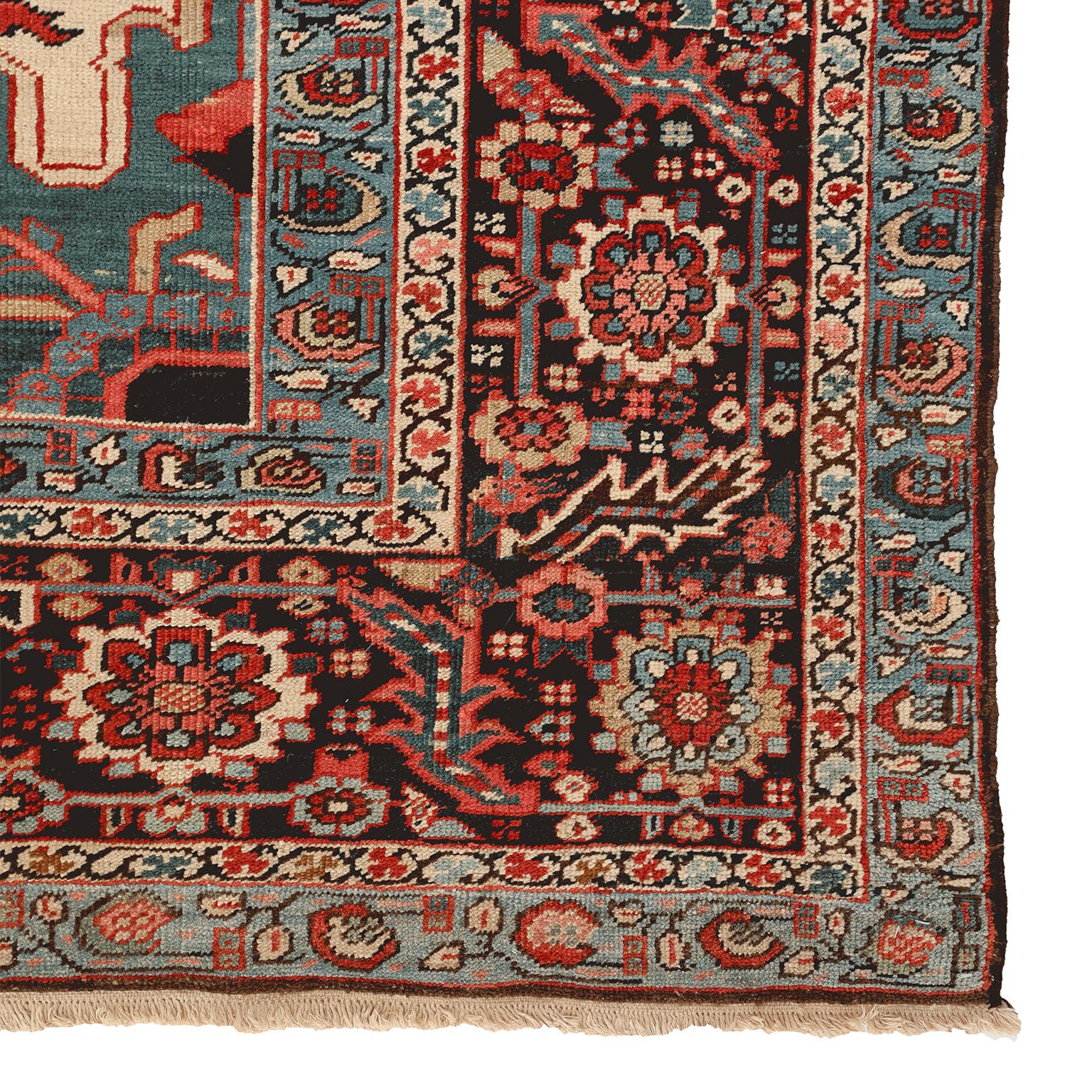 This Heriz Serapi Persian carpet circa 1900 in pure wool and vegetable dyes features a central octagonal medallion and multiple borders in organic colors of red, blue, green, cream, brown and indigo. Natural color variation and striation add further