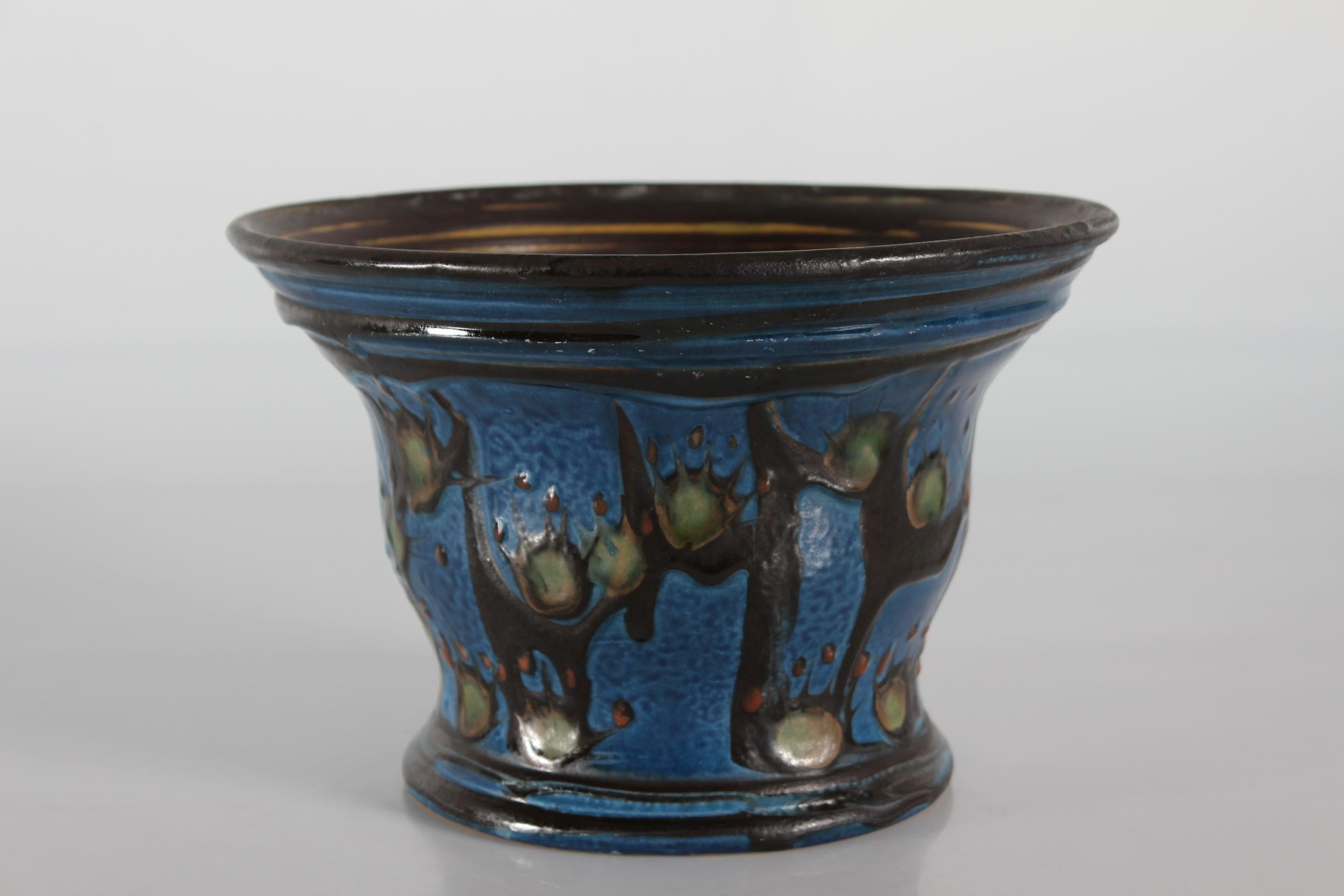 Jugendstil-Blumentopf aus Keramik, hergestellt von Herman A. Kähler Keramikwerke in Dänemark im Zeitraum 1925-1935
Der Blumentopf wird von Hand mit der speziellen Kuhhorn-Technik verziert. Die Glasur ist dunkelblau, rostbraun, grün und