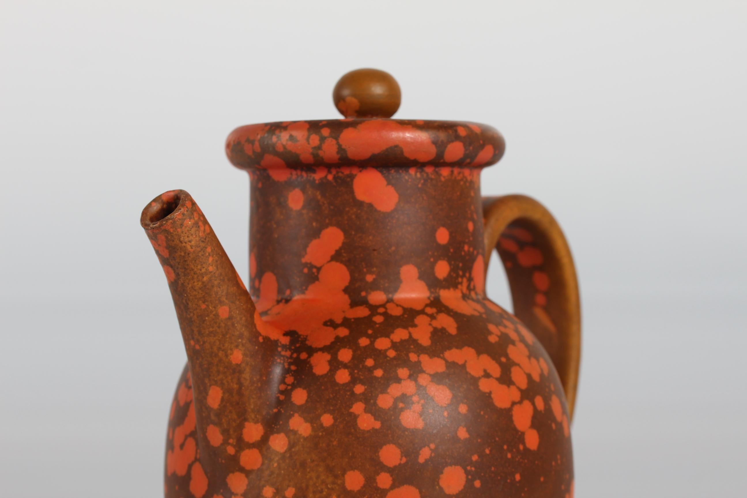 Ceramic coffee pot/pitcher with lid designed by Nils Kähler and manufactured by Herman A. Kählers ceramic workshop 
The coffee pot is decorated with an orange speckled uranium glaze and has the signature HAK + Denmark

Measures: Height 22