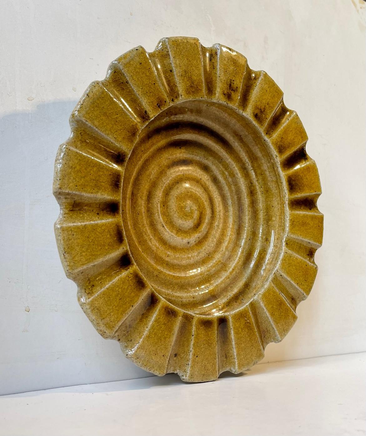A rare stoneware bowl executed with wide ribbings and core yellow glaze. Designed by Danish Ceramist Hjalmar Møller and made at Kähler during the 1930s or 40s. Measurements: D: 27 cm, H: 6 cm. Fully signed and marked to its base.