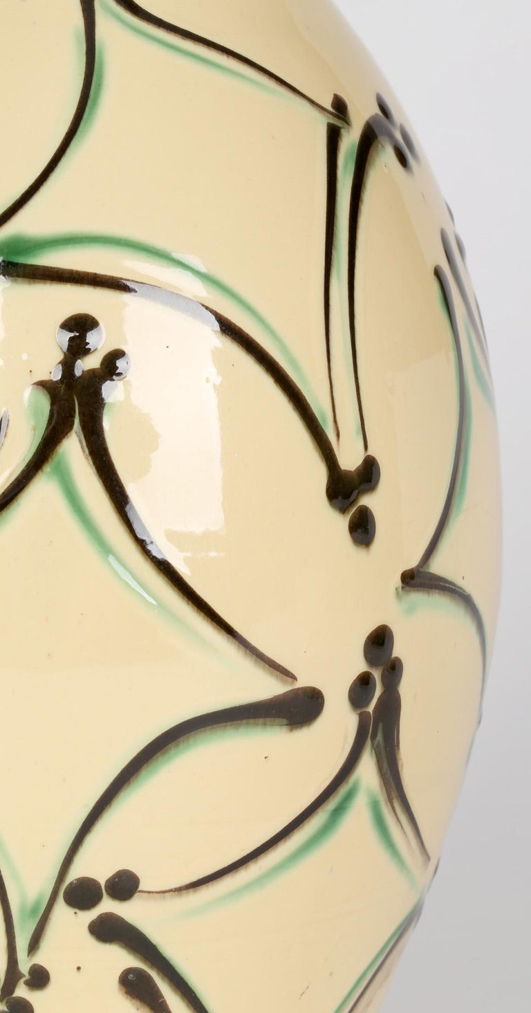 A large and impressive Danish art pottery vase decorated with brown and green slip patterns on a cream ground by Herman August Kahler (1846-1917) for Kahler Keramiks and dating from around 1910. The tall bulbous shaped vase stands on a narrow