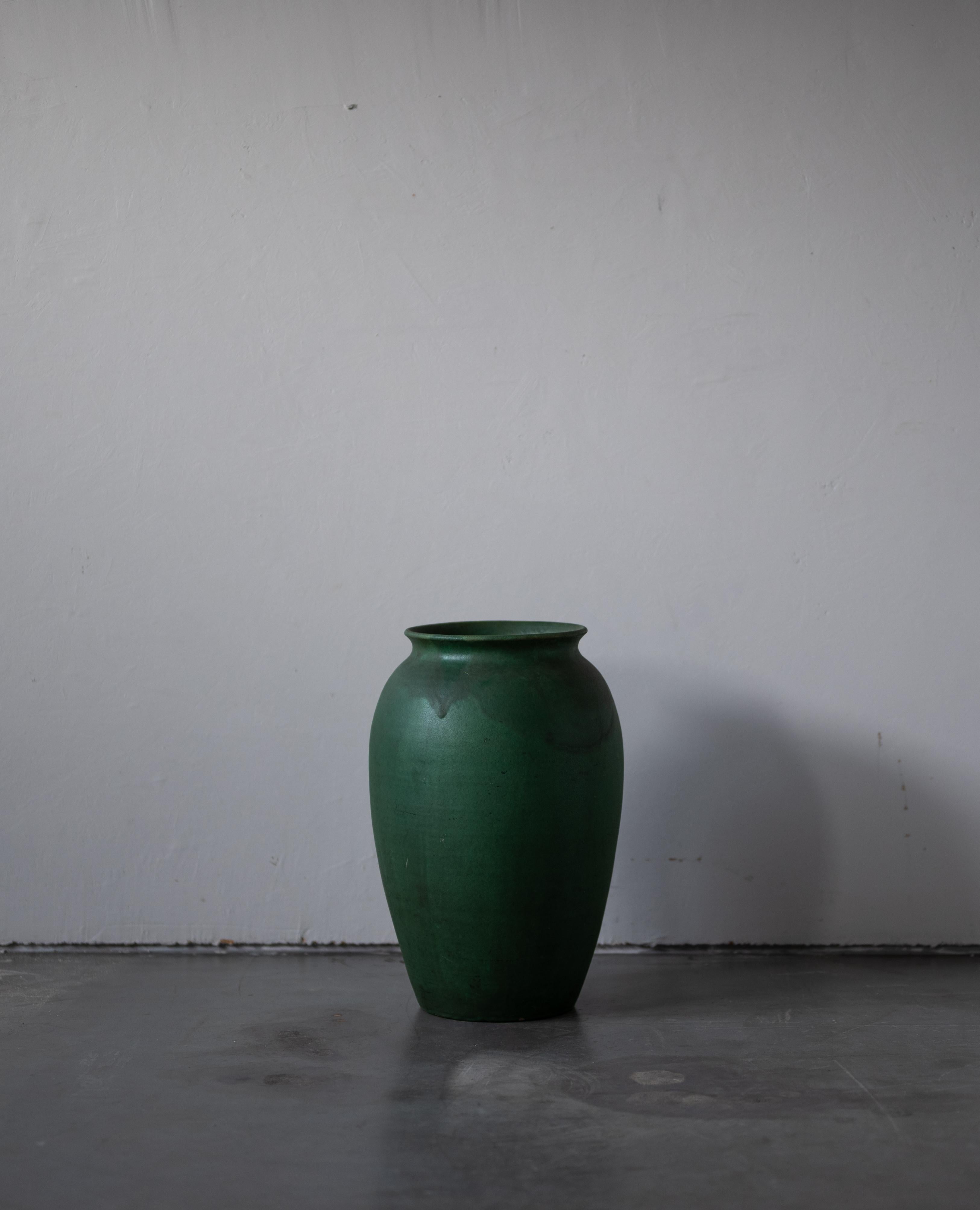 A very large vase. Designed and produced by Herman Kähler. Signed HAK. 

As is Kählers signature, the clay was sourced on the island of Bornholm. On this vase, a green glaze has been applied.

Kähler is an important ceramicist known for his