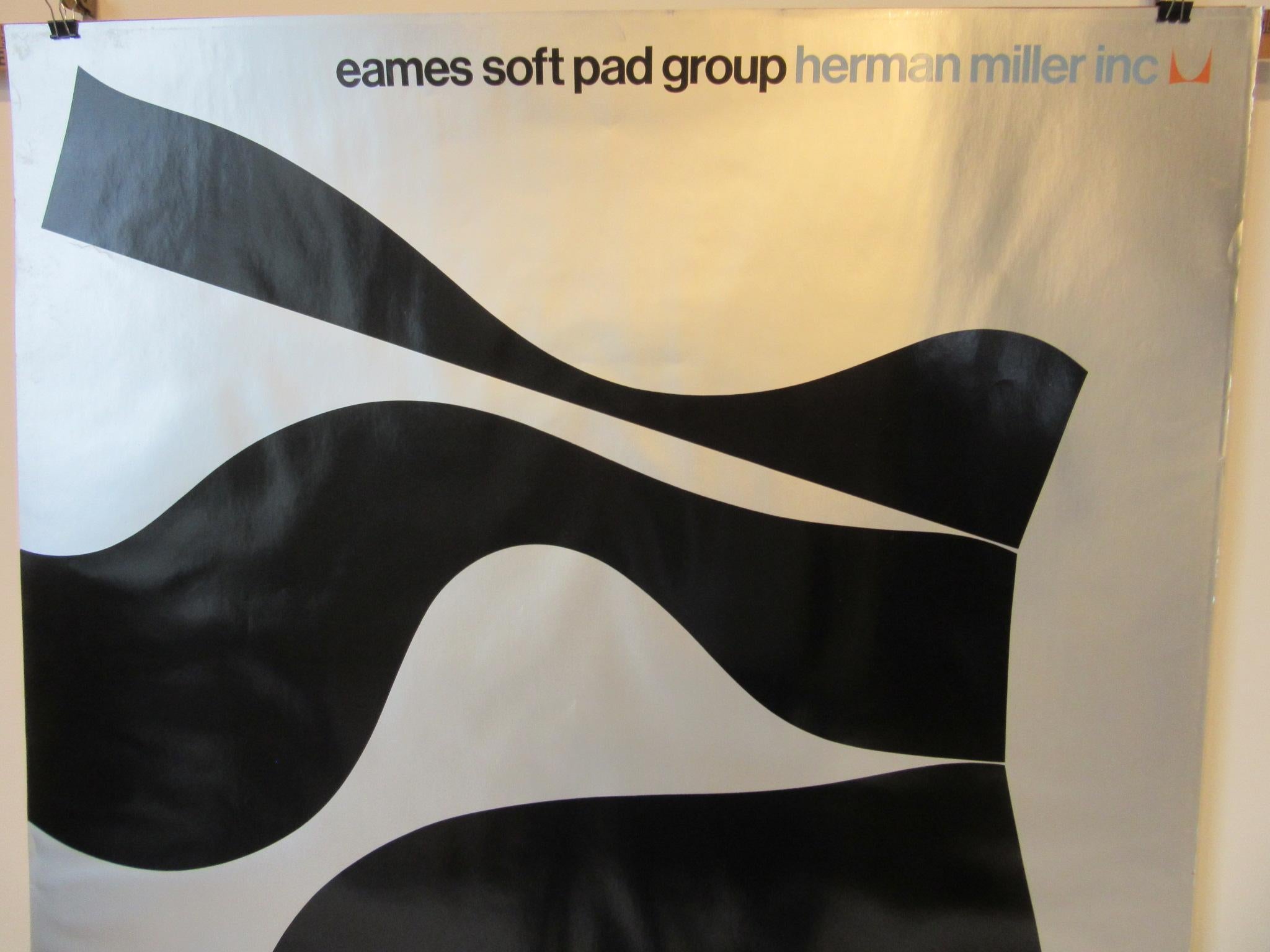 A Herman Miller dealer display poster with silver and black lithograph mod design for the Soft Pad Group chair sets. A rare and hard to find poster with text to the top and the Miller icon in orange and turquoise with black floating seat forms on a