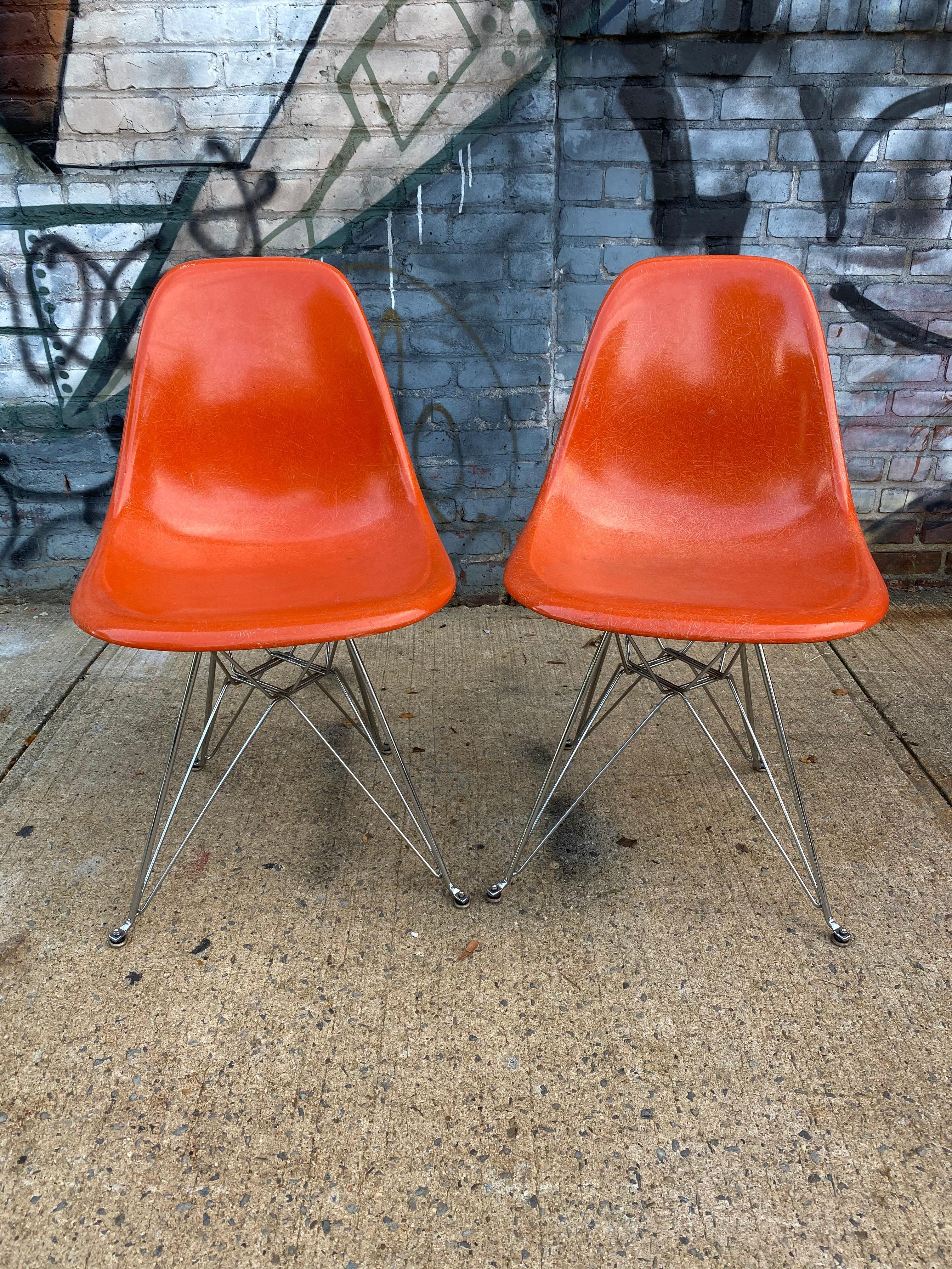 Elegant pair of matching Herman Miller Eames dining chairs. Brilliant red orange vintage fiberglass shells on newer production chrome Eiffel bases. All glides and mounts intact. Real vintage Herman Miller screws.
Shells embossed Herman Miller and
