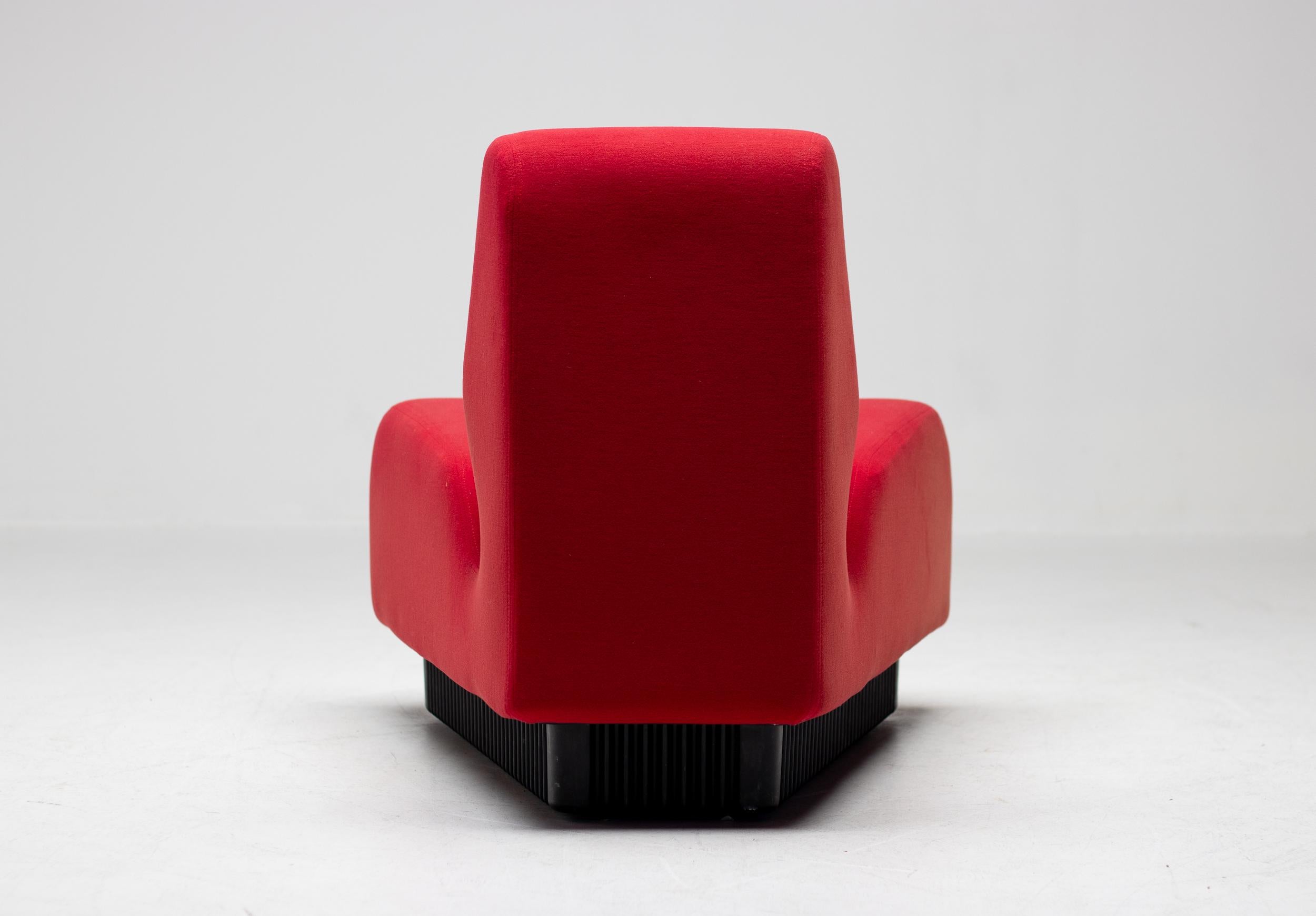 A single modular Don Chadwick seating piece set in a red fabric with black ABS plastic base. This pie shaped seating piece is covered in a contract fabric that is soft and able to stretch a bit to conform to the shape. Manufactured by the Herman