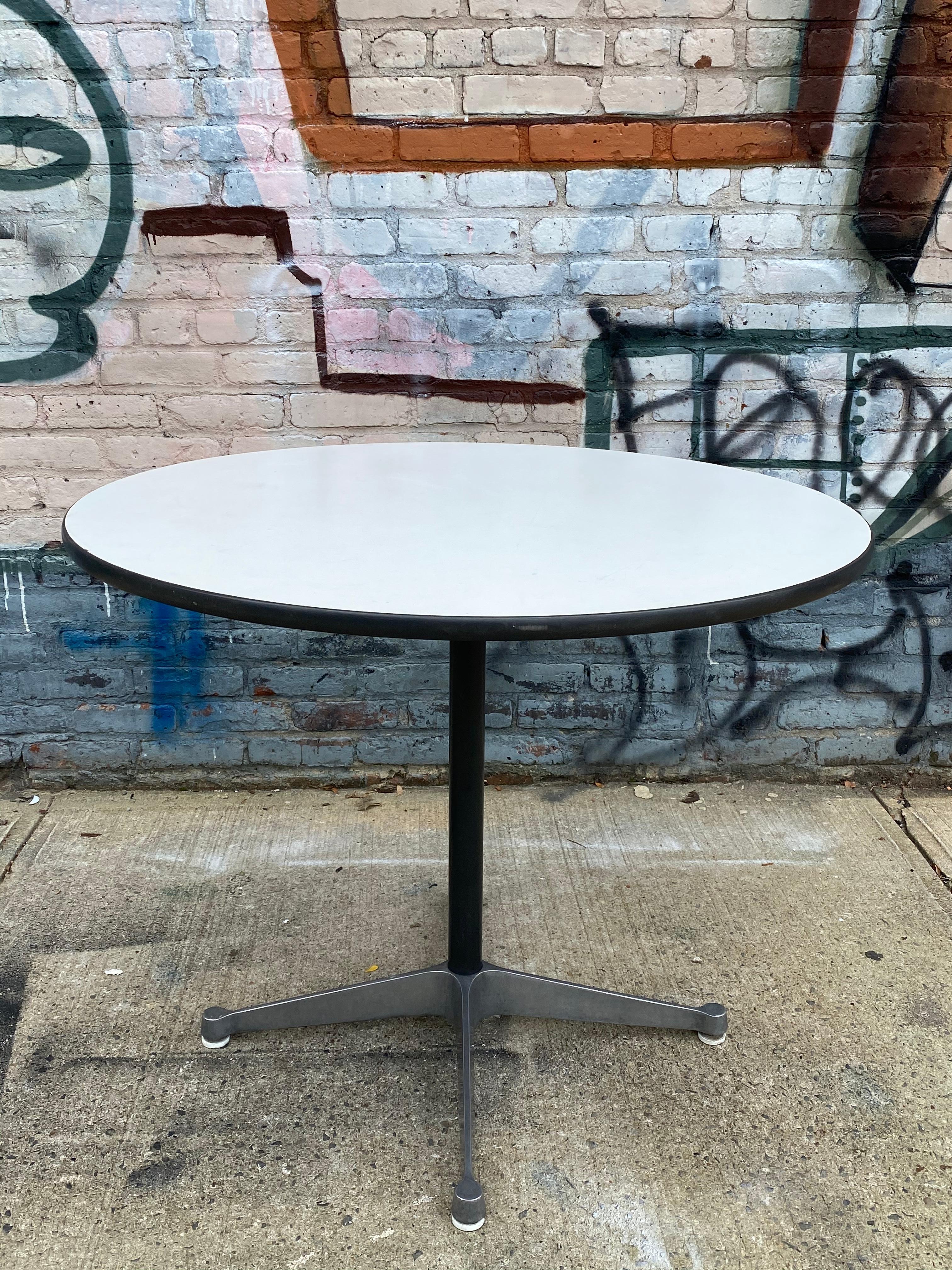 Wonderful example of the Classic Eames dining table for Herman Miller. 36 inch diameter with durable laminate top. Signed and guaranteed authentic. Great for up to 4 people. On sturdy Herman Miller contract aluminum four star base. Pair of Eames