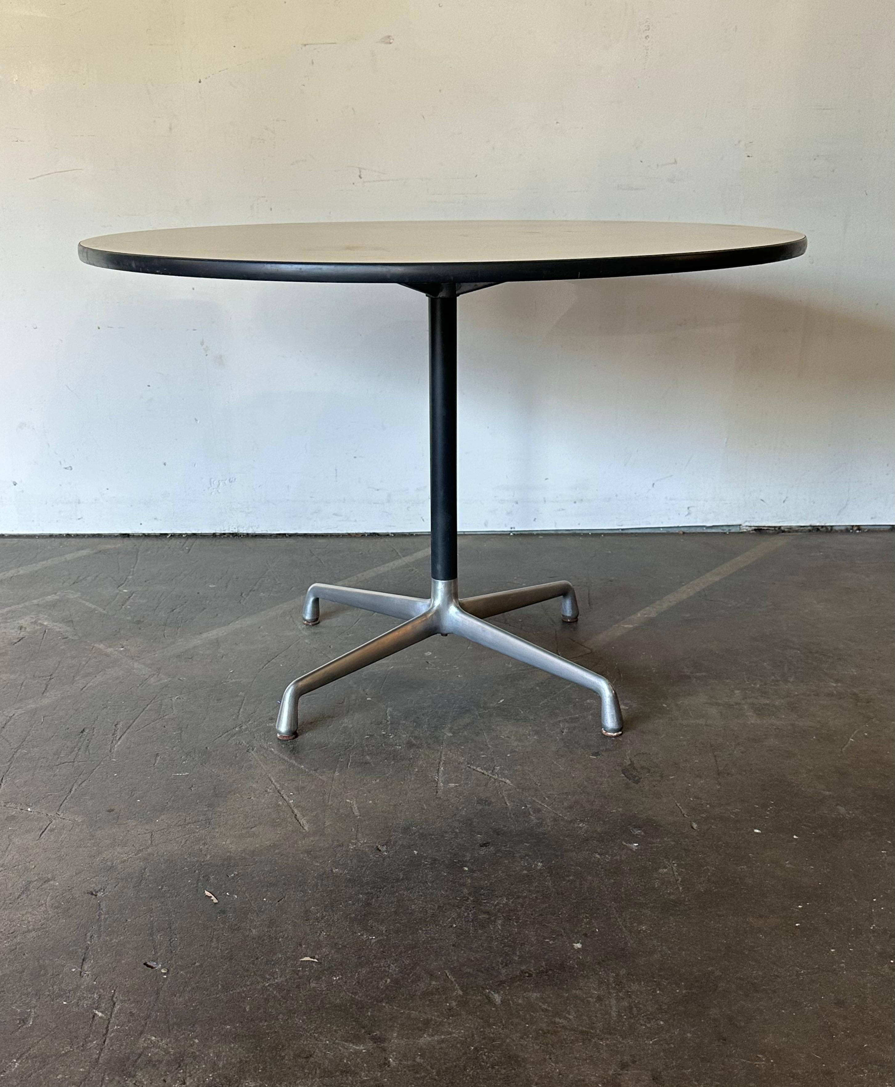 Herman Miller Eames dining table. Circular top with 42” diameter. Cast aluminum base. Off white laminate surface in very good condition. Base in good shape. Signed and guaranteed authentic. Banding in good condition. Comfortably fits 4 chairs, room