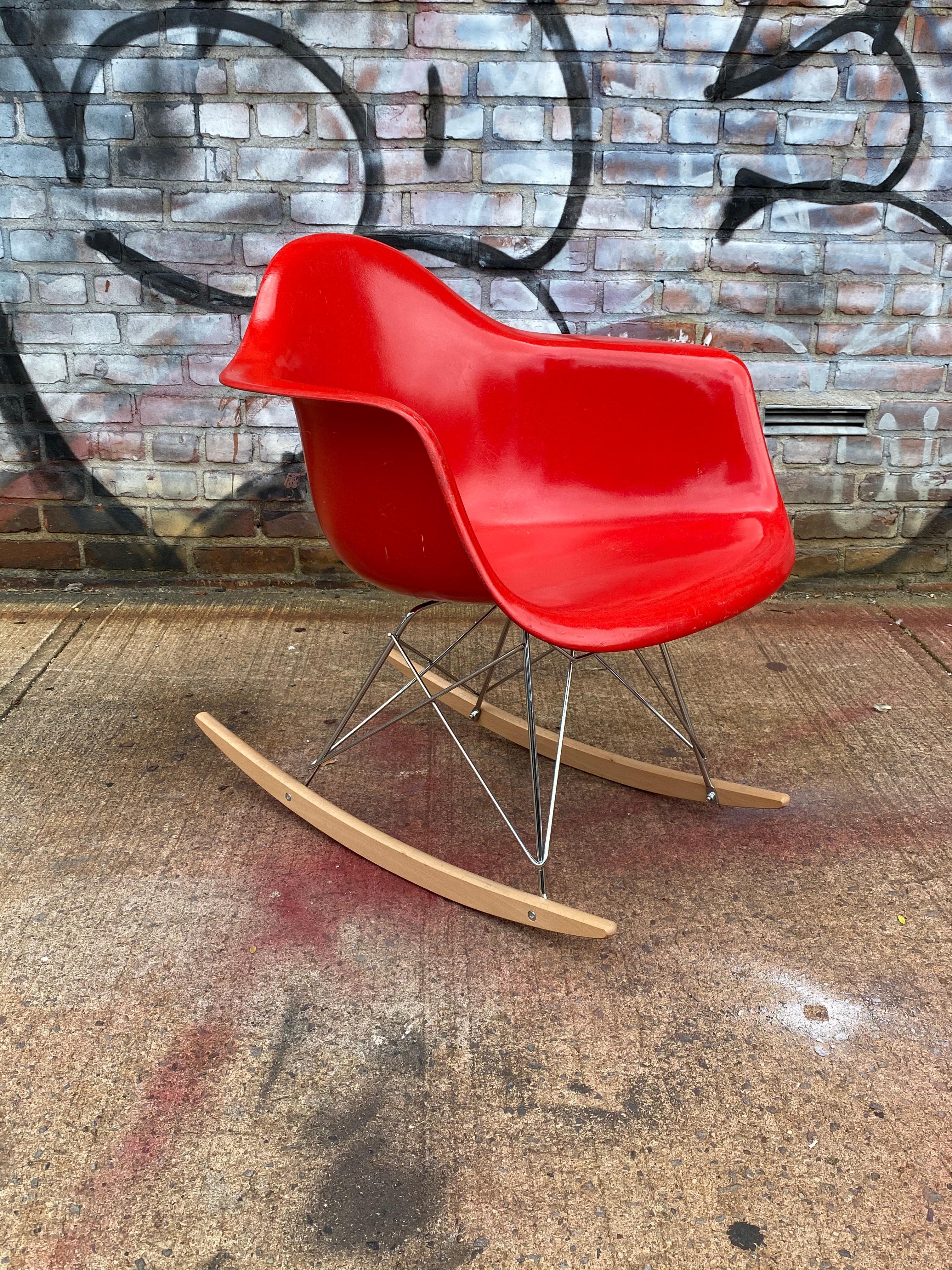 Bright and bold example of the classic design icon. This Eames rocker features a cherry red fiberglass shell, signed Hermon Miller and guaranteed authentic. It presents in very good vintage condition with no breaks. Base comprised of light wood