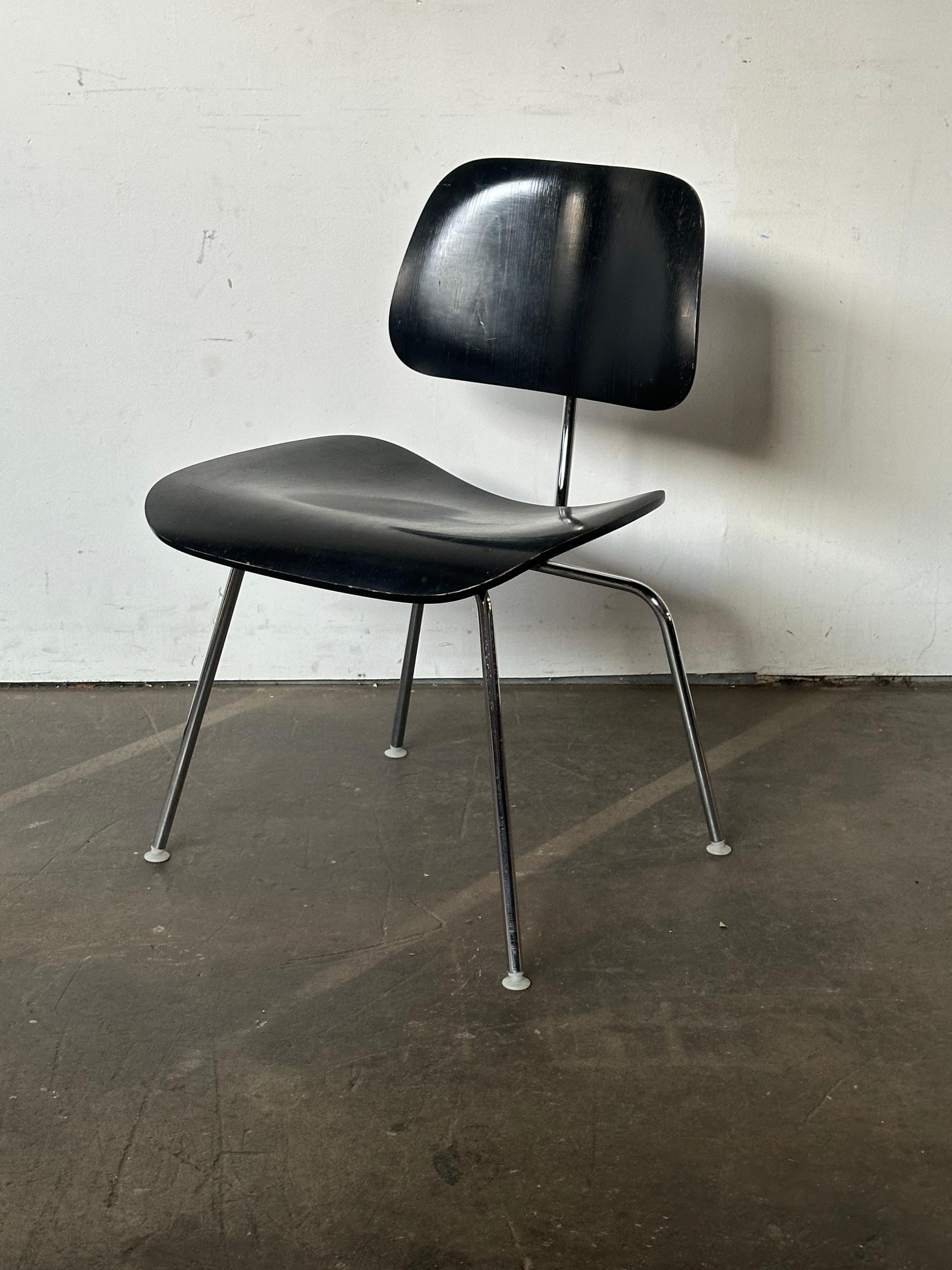 Classic Herman Miller Eames DCM dining chair. Ebonized molded wood seat and back, supported by chrome steel rod frame. All screws and self leveling nylon feet intact. Signed and guaranteed authentic. Circa 1970s/1980s production. Also perfect as a