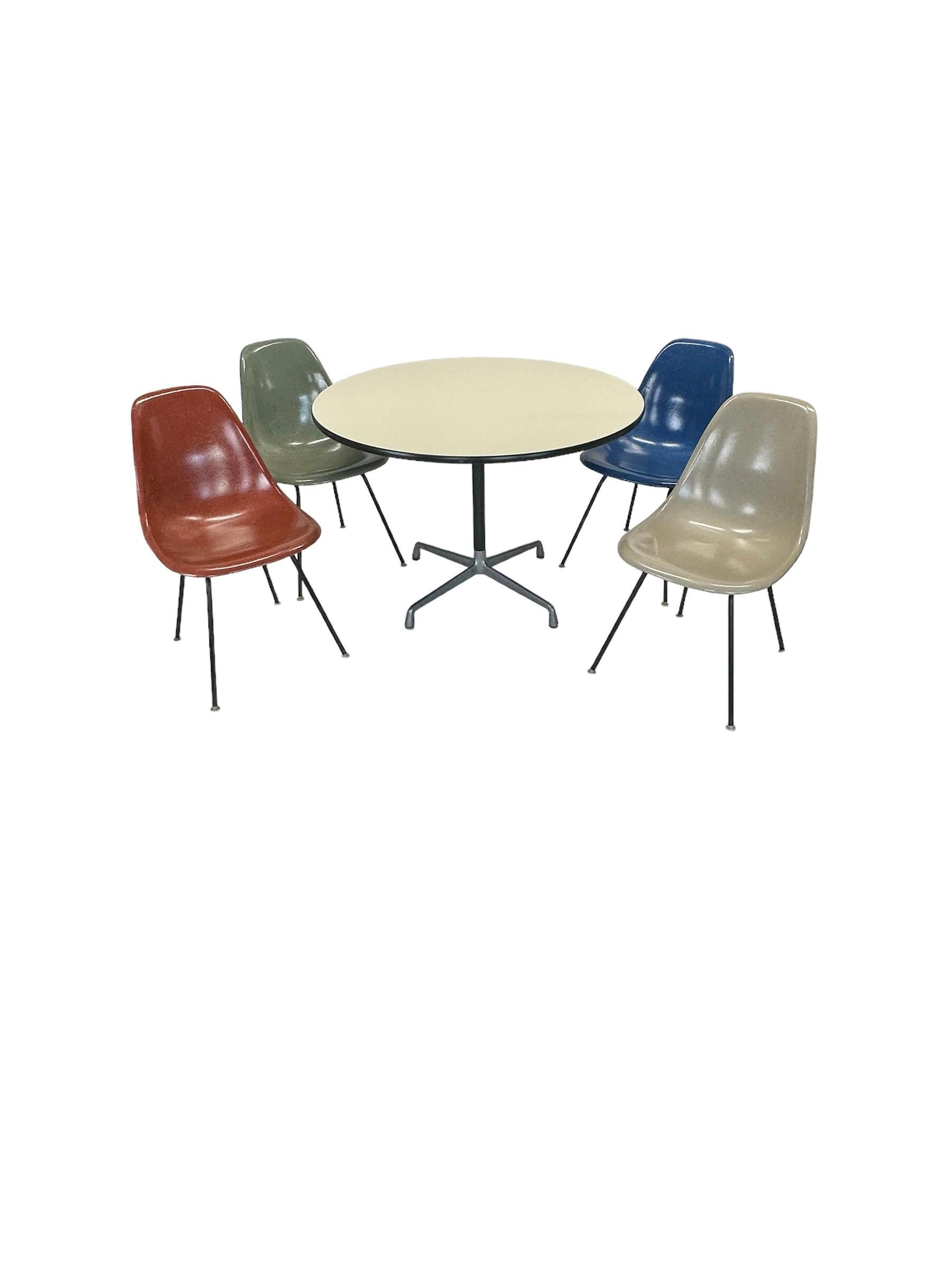 Original signiertes Herman Miller Eames Esstischset. Mit mehrfarbigen Schalenstühlen auf schwarzen H-Füßen. Alle selbstnivellierenden Stuhlgleiter aus Nylon sind intakt und können auf verschiedenen Oberflächen verwendet werden. Alle Stühle und