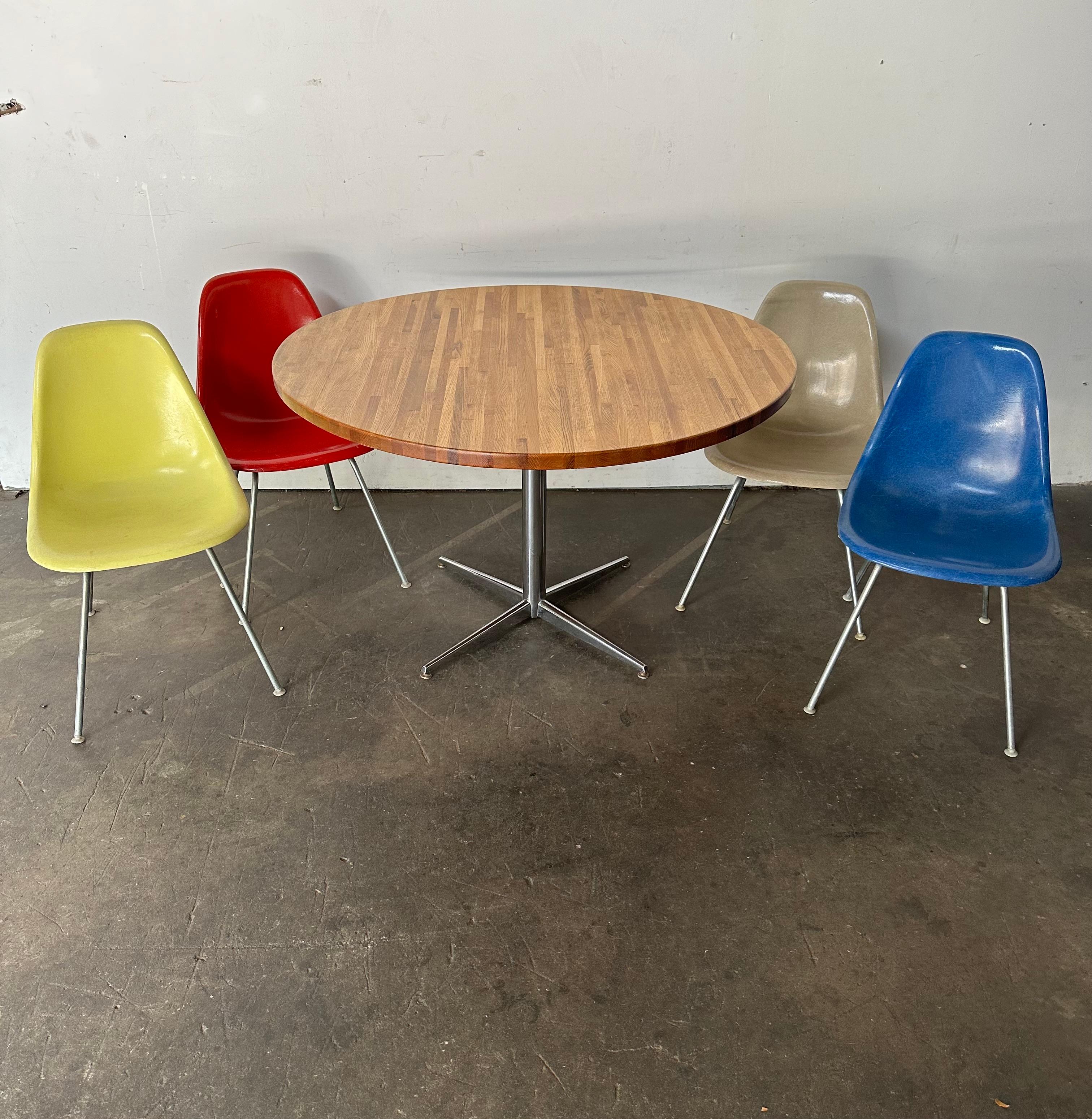 Les chaises classiques Eames à coquilles sont associées à une table en bois massif. Coquilles multicolores en fibre de verre moulée dans un assortiment de couleurs amusantes, avec des cadres en métal et des patins de sol en nylon autonivelants, sans