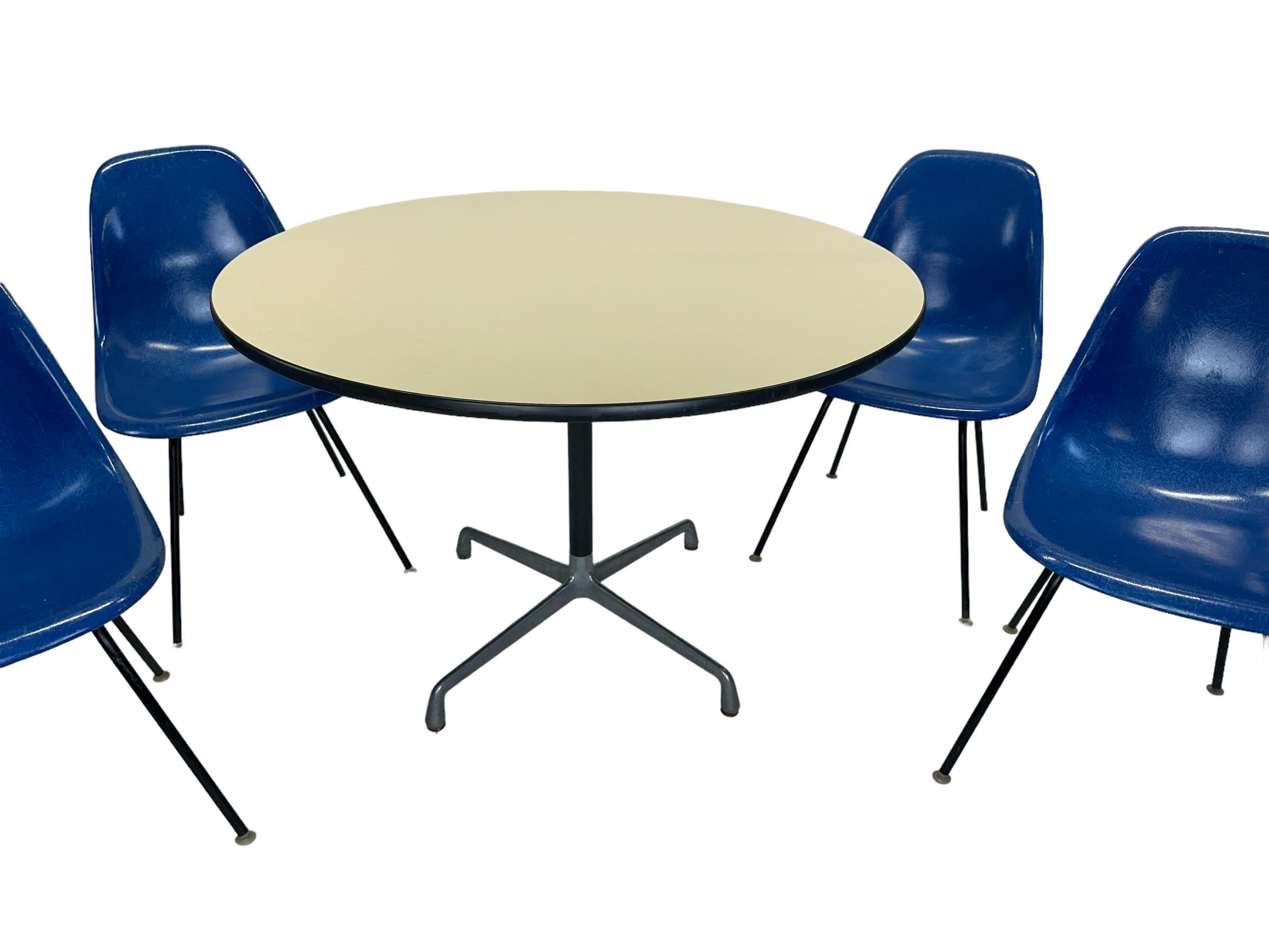 Beautiful vintage Herman Miller Eames dining set. Featuring 48 inch diameter round dining table with four matching fiberglass chairs. Table and chairs all signed and guaranteed authentic Herman Miller production. Ultramarine blue chairs are a very