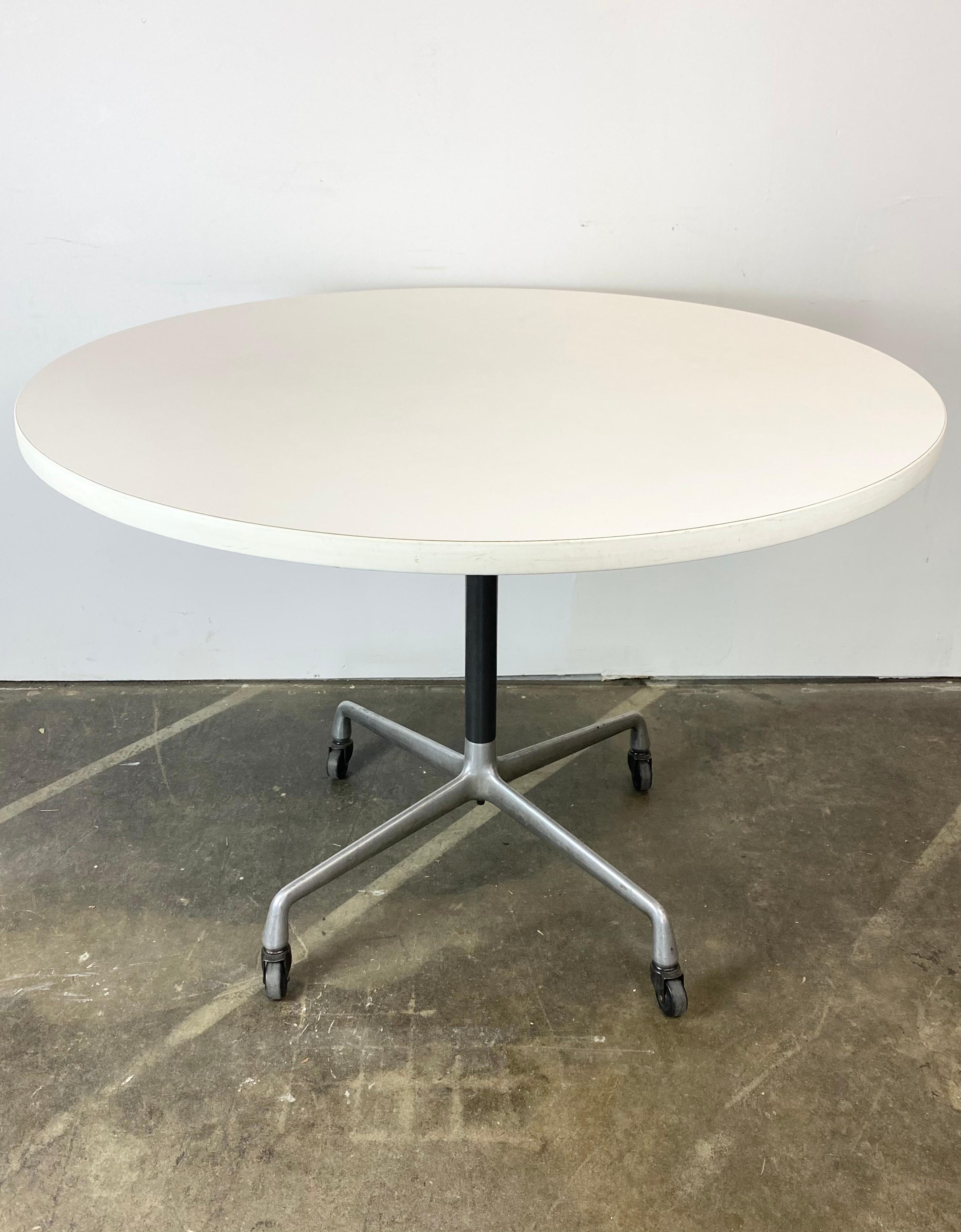Pleased to offer this classic Herman Miller Eames dining table. Circular tabletop, 42 inches in diameter. With white edge and white laminate too. No egregious wear to the surface. Aluminum pedestal base on casters provide an extra utility function