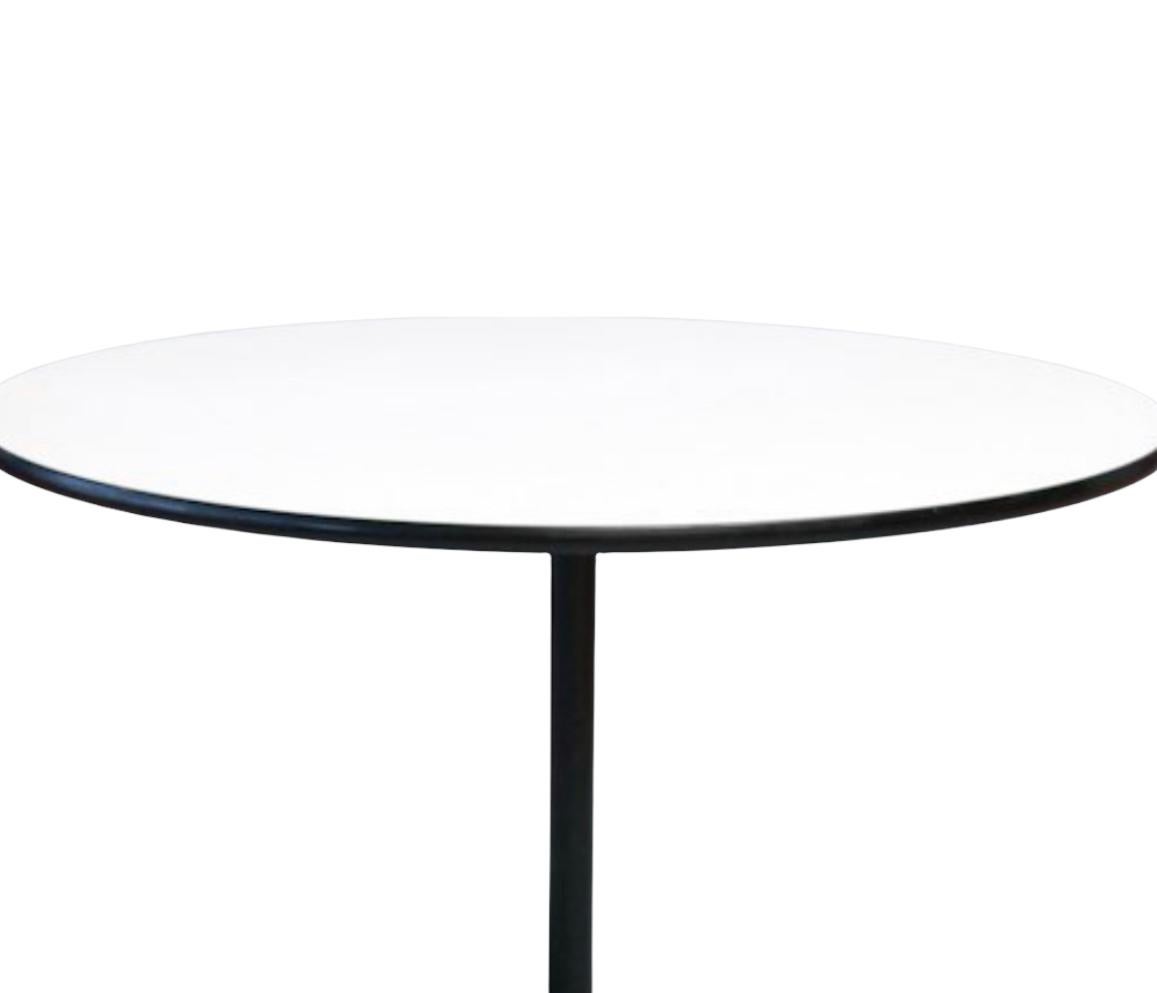 Classic Herman Miller Eames dining table. Model 650, executed in white Formica durable top with black banding and cast aluminum base. All glides present. Base and pole repainted and in good condition. 48 inch diameter, circular top, accommodates up