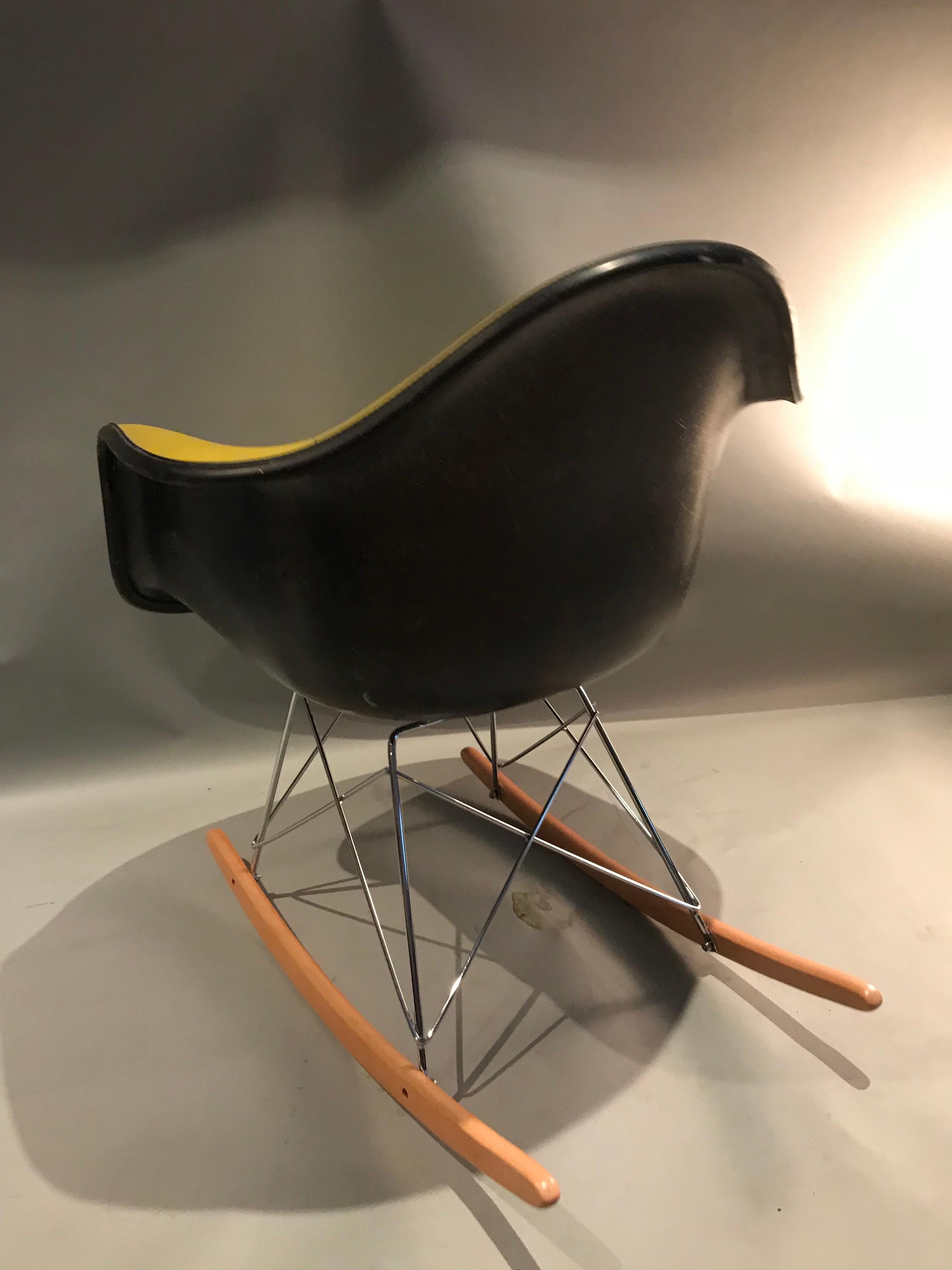 Beautiful Herman Miller Eames fiberglass rocking chair. Herman Miller stamped shell with yellow Naugahyde upholstery. Vintage shell circa 1960s-1970s with newer base.