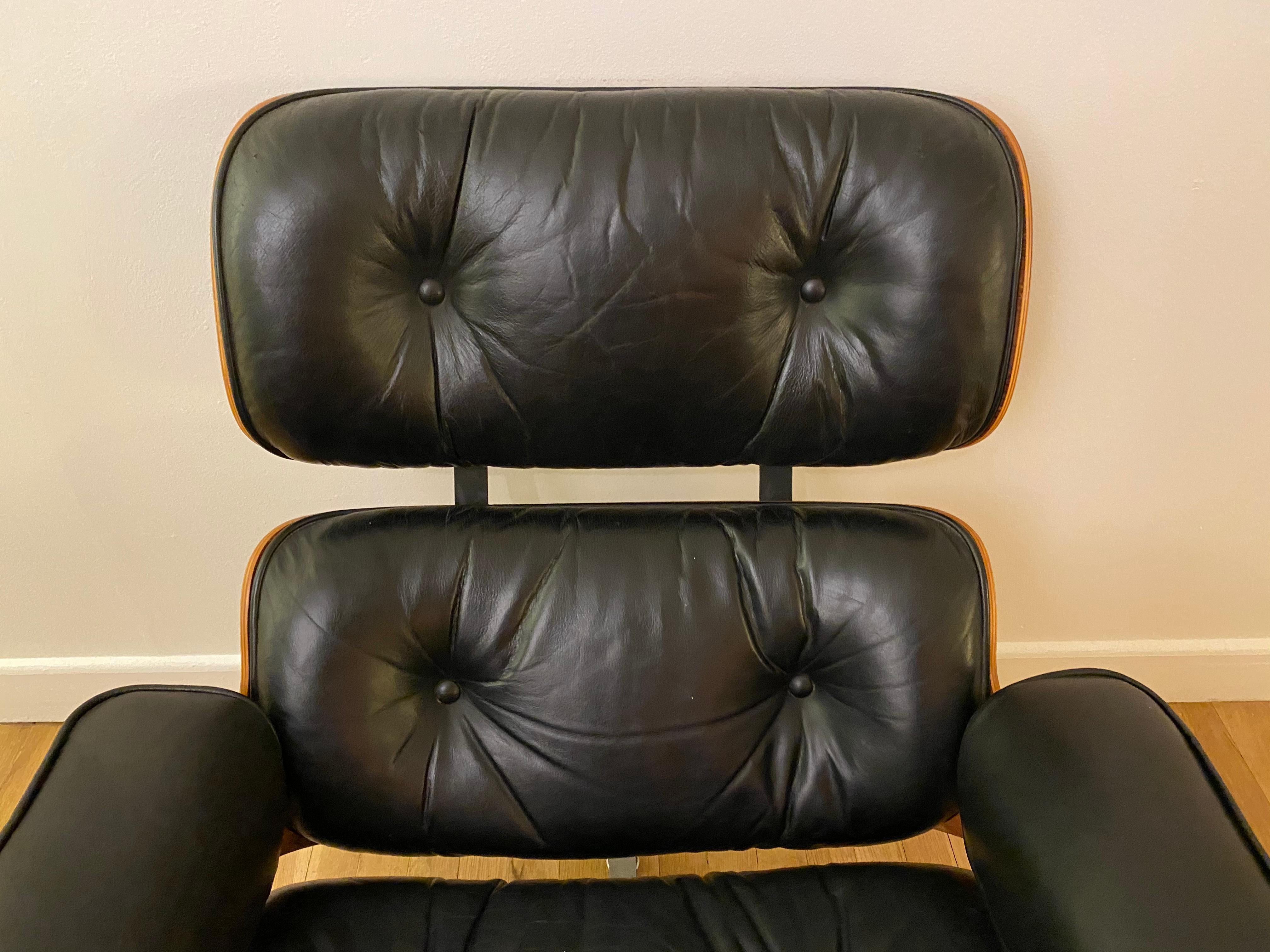 Classic Eames lounge chair and ottoman with black leather cushions. Signed and guaranteed authentic. Handsome color and grain texture. Cushions with all buttons intact. No missing parts. New shock mounts professionally installed. Adjustable glides