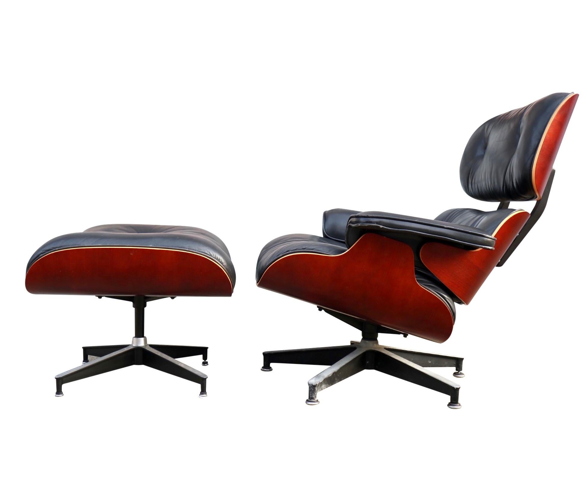 Gorgeous Eames lounge and ottoman designed by Charles and Ray Eames. Signed and manufactured by Herman Miller. Warm cherry panels with original black leather cushions on cast aluminum base. Chair swivels on base and both chair and ottoman have