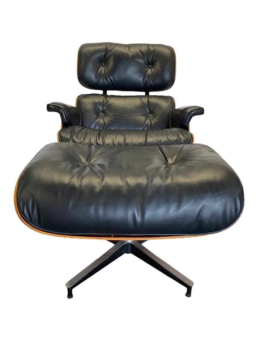 Superbe fauteuil de salon classique Eames et ottoman. Exécuté en bois de rose et en cuir noir. Bases en aluminium moulé, avec patins de mise à niveau réglables 