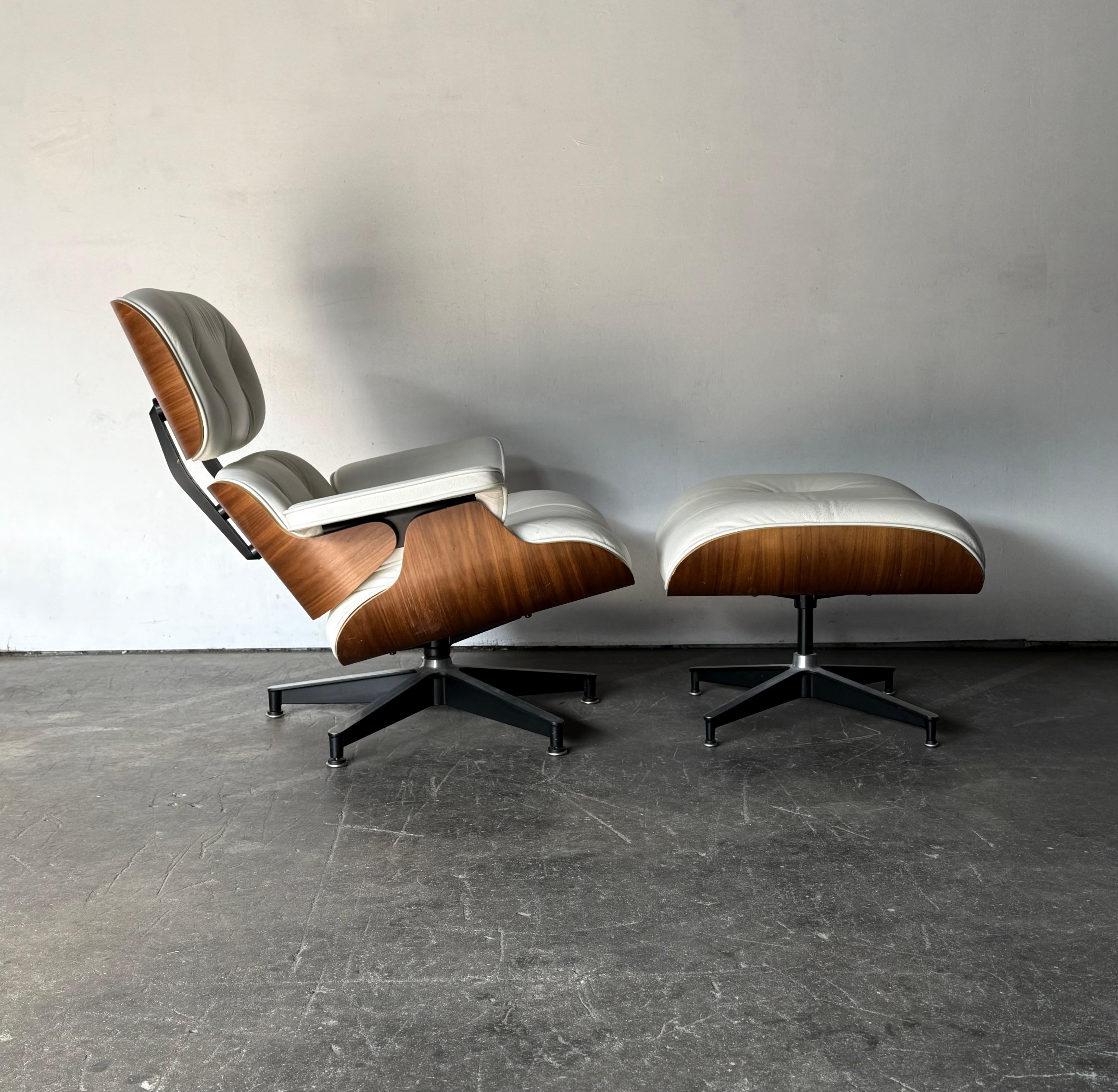 Preciosa silla y otomana clásicas Eames. Piel de marfil con cáscaras de nuez aceitadas. Silla y otomana firmadas. No faltan piezas. Los paneles de madera se presentan bien, con colores uniformes y veteados equilibrados. Piel sin desgarros ni falta