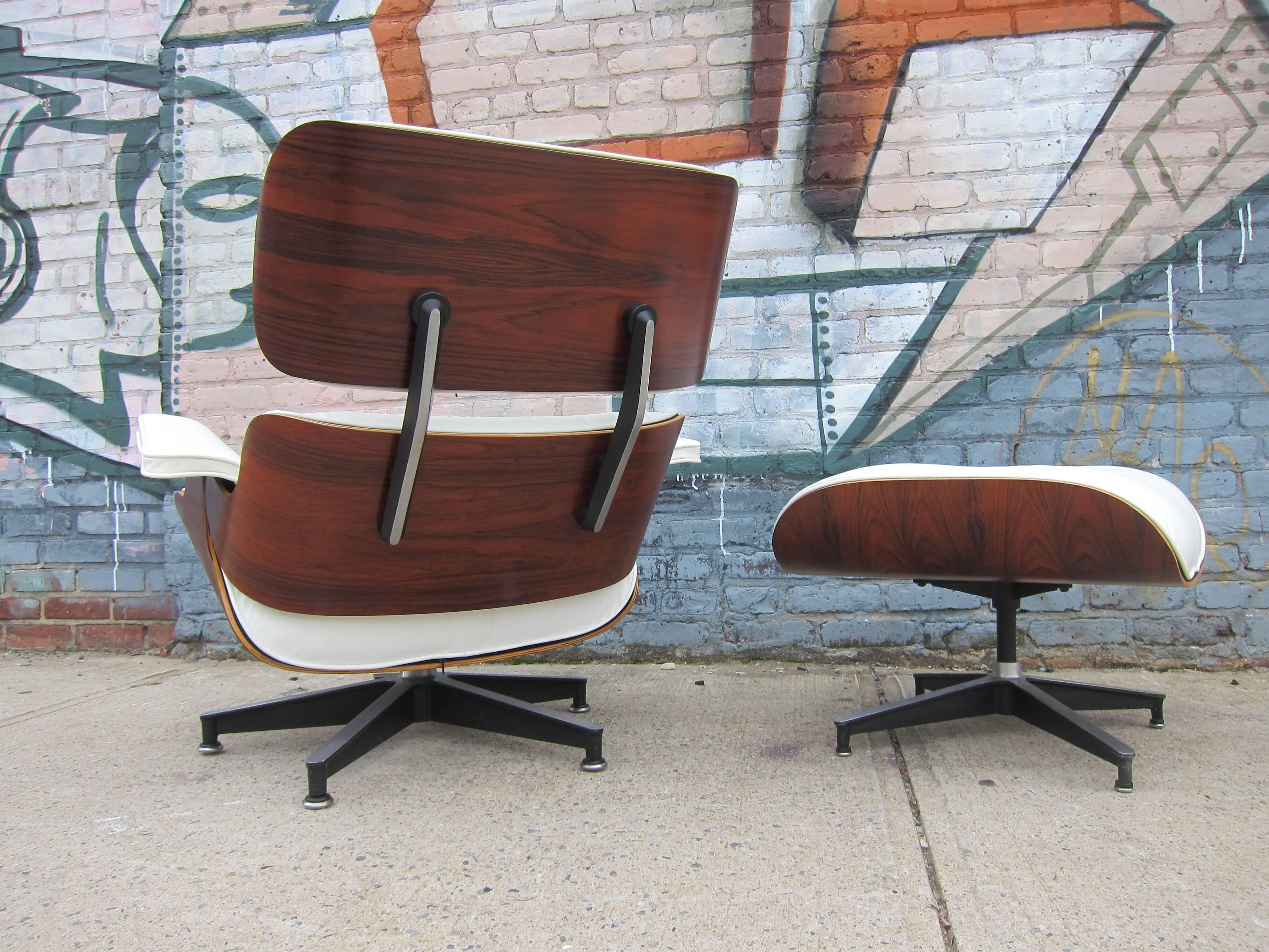 Herman Miller Eames lounge chair and ottoman. Features vintage rosewood shells that have been professionally restored along with perfect new custom made cushions with white leather. Signed Herman Miller. The wood boasts deep and rich colors and