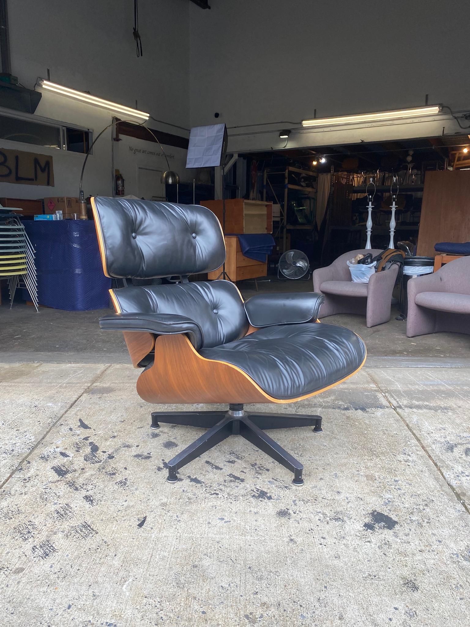 A stellar example of the classic Eames 670 lounge chair. Soft black leather cushions in walnut shells and aluminum swiveling base. All adjustable leveling glides intact. Gorgeous walnut wood tones and detailed grain features. Signed and guaranteed