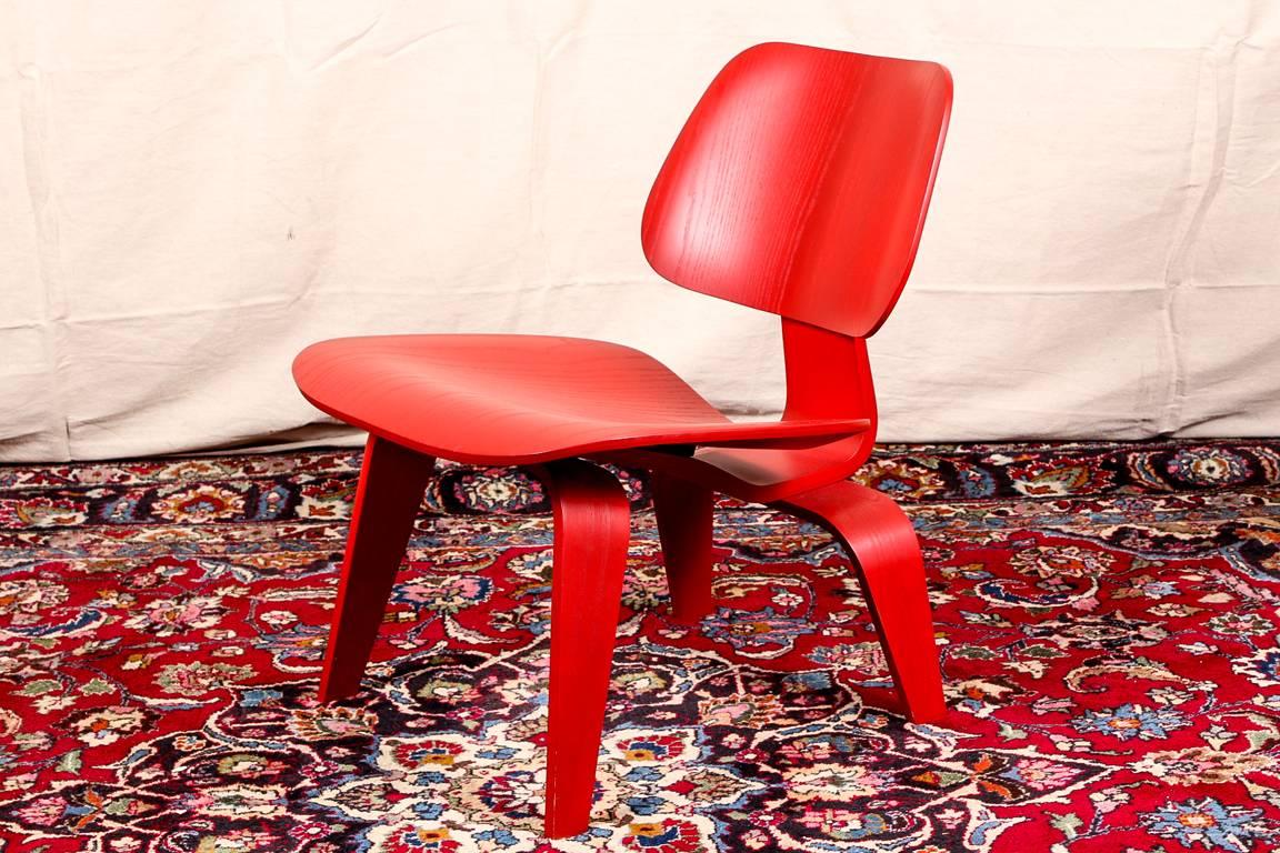 Herman Miller Eames modern red stained wood side chair, shaped seat on a curved tapering legged frame, labeled on underside, back attachment with black rubber disks.

Condition: Expected surface wear and signs of use including very light and