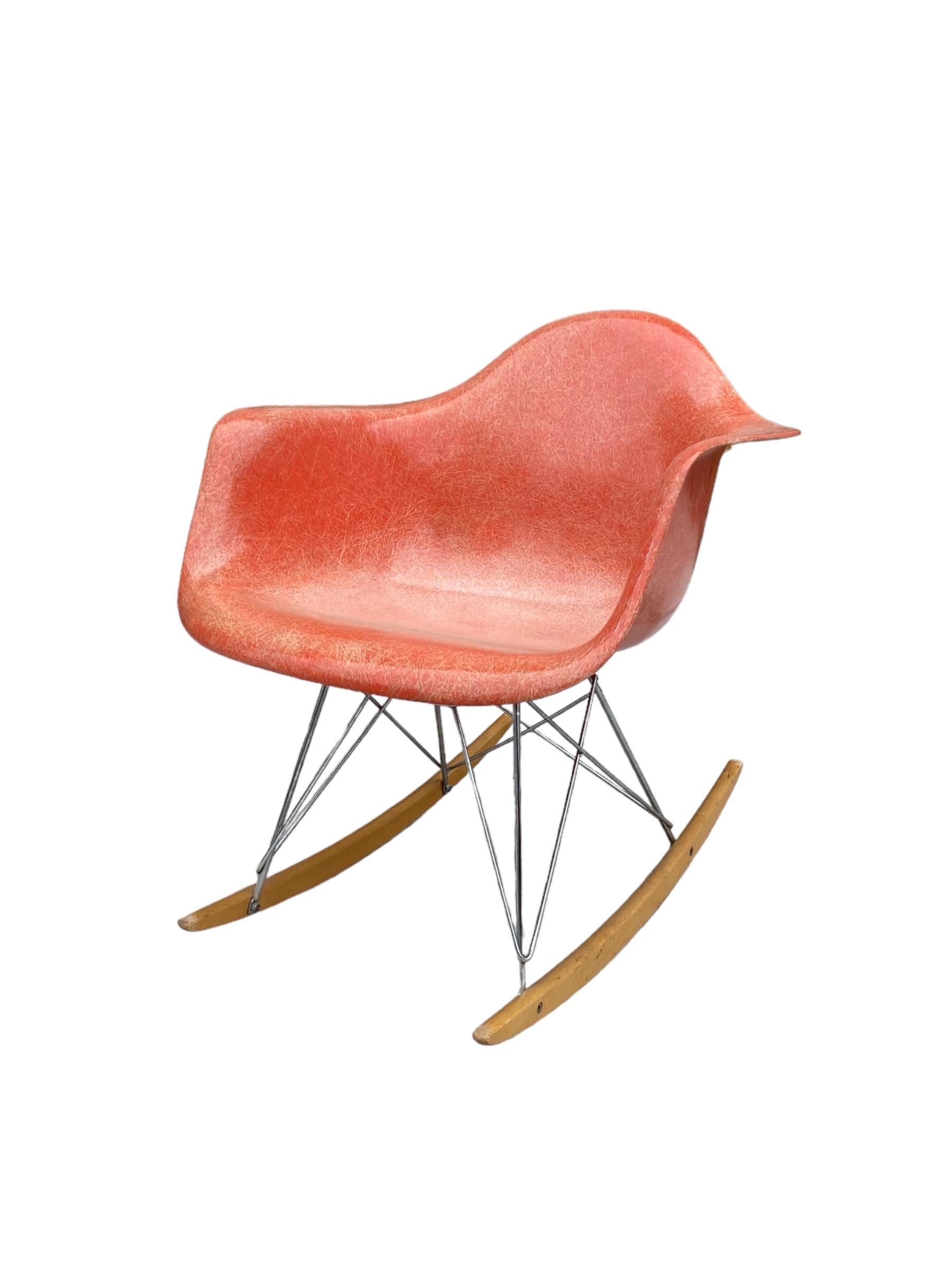 Hübsche Herman Miller Eames Glasfaserschale aus den 1950er Jahren auf späterem Wippfuß. Rot-orangefarbenes Fiberglas mit spektakulärem Faserkontrast. Gestell aus verchromtem Stahl mit Kufen aus Ahornholz. Signiert unter dem Schalensitz mit